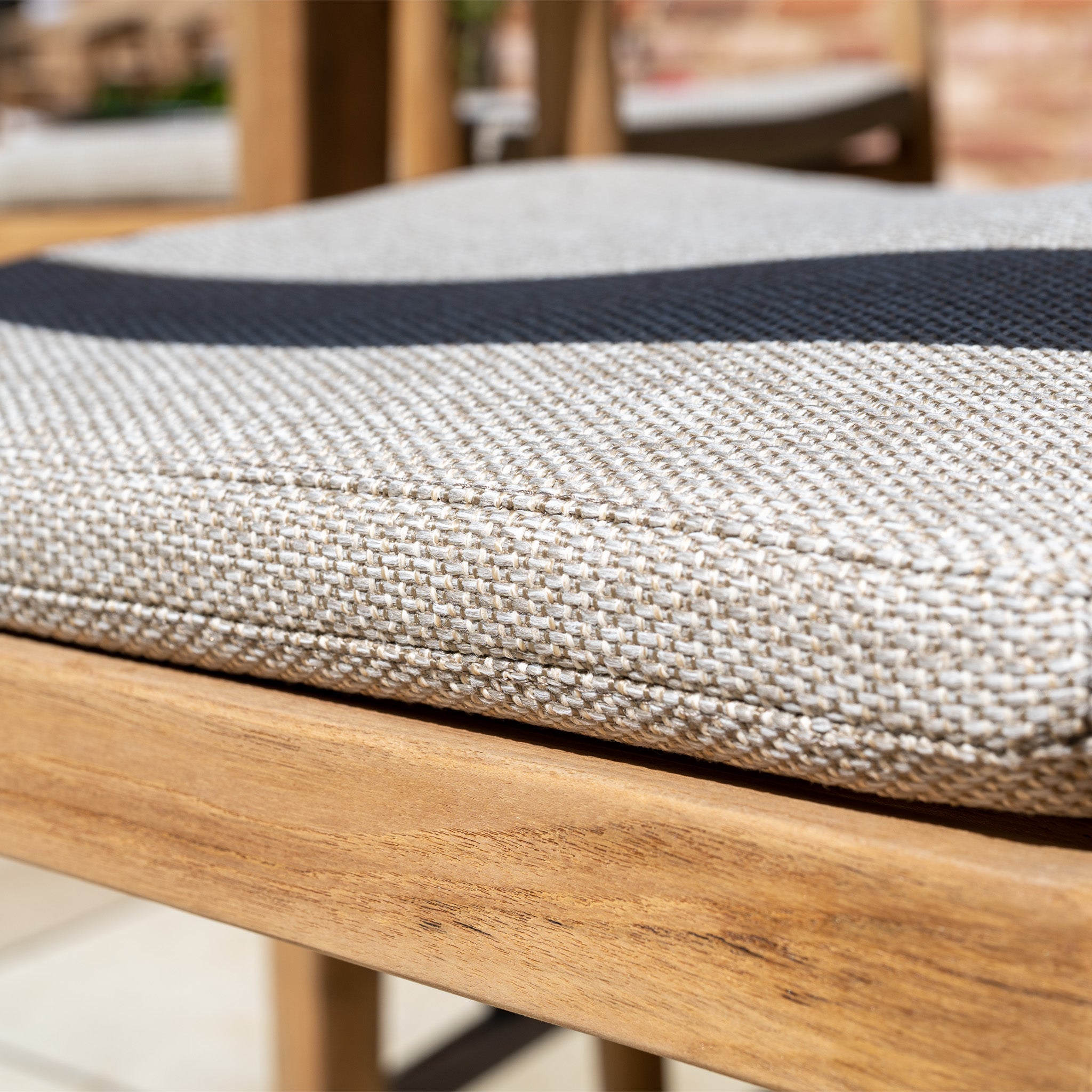 Close-up of a beige textured seat cushion on the Siena 8 Seat Dining Set with Ceramic Top Table in Fawn, featuring a black stripe detail.