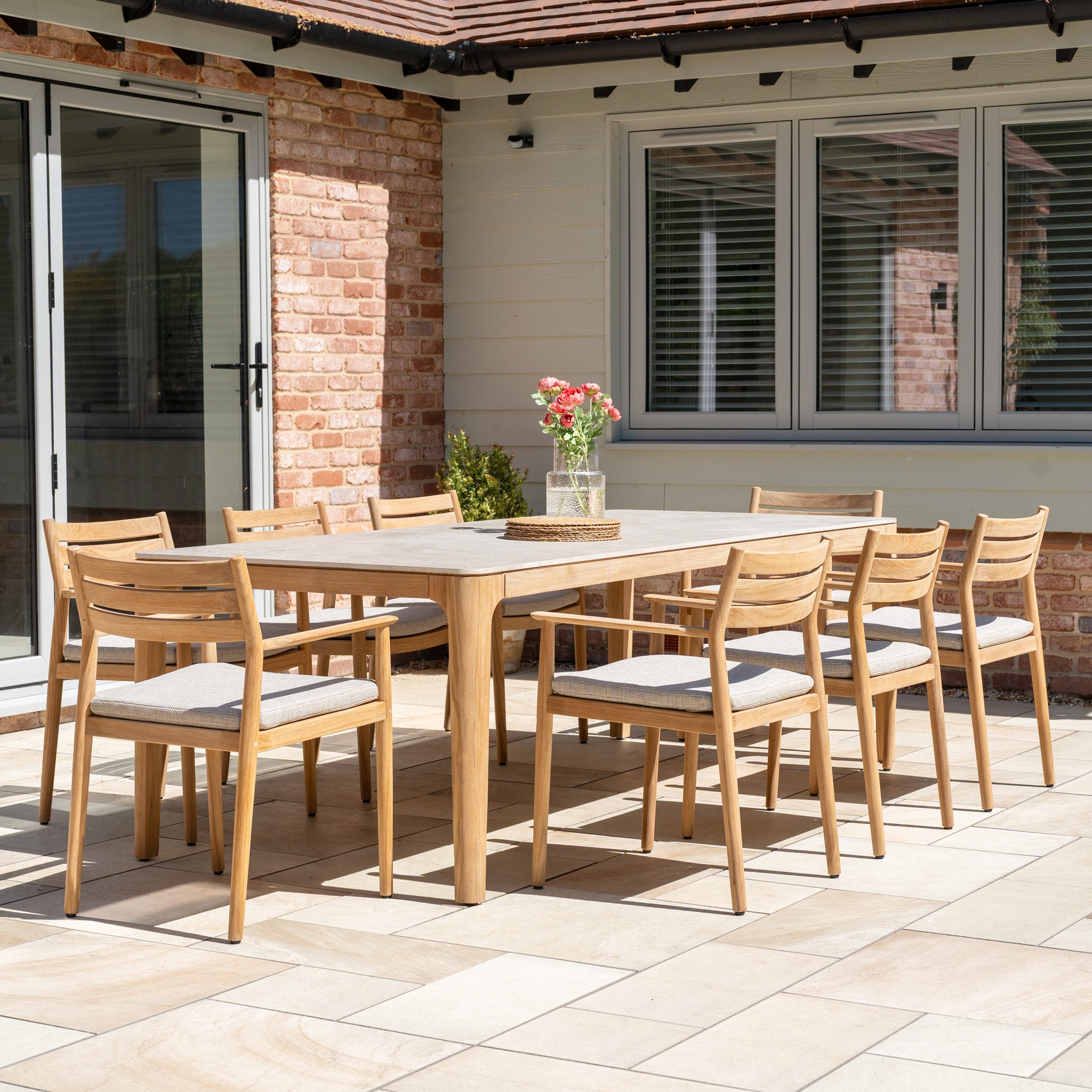 The Siena 8 Seat Dining Set with Ceramic Top Table in Fawn offers elegant outdoor dining for eight, perfect for gatherings on the tiled patio.