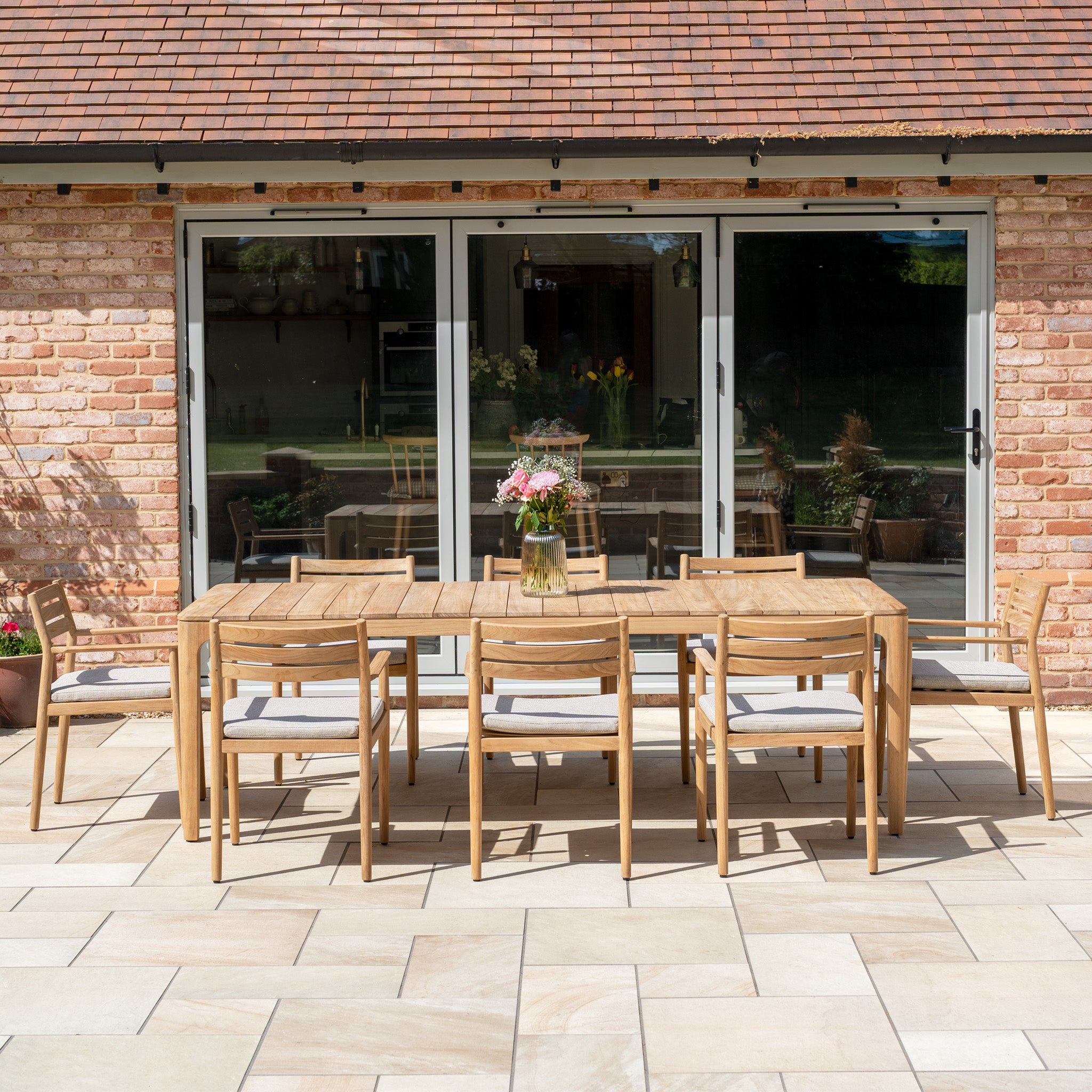 The Siena 8 Seat Dining Set with Teak Table in Fawn—complete with eight chairs—is the ideal outdoor furniture for stylish patio gatherings by glass doors.