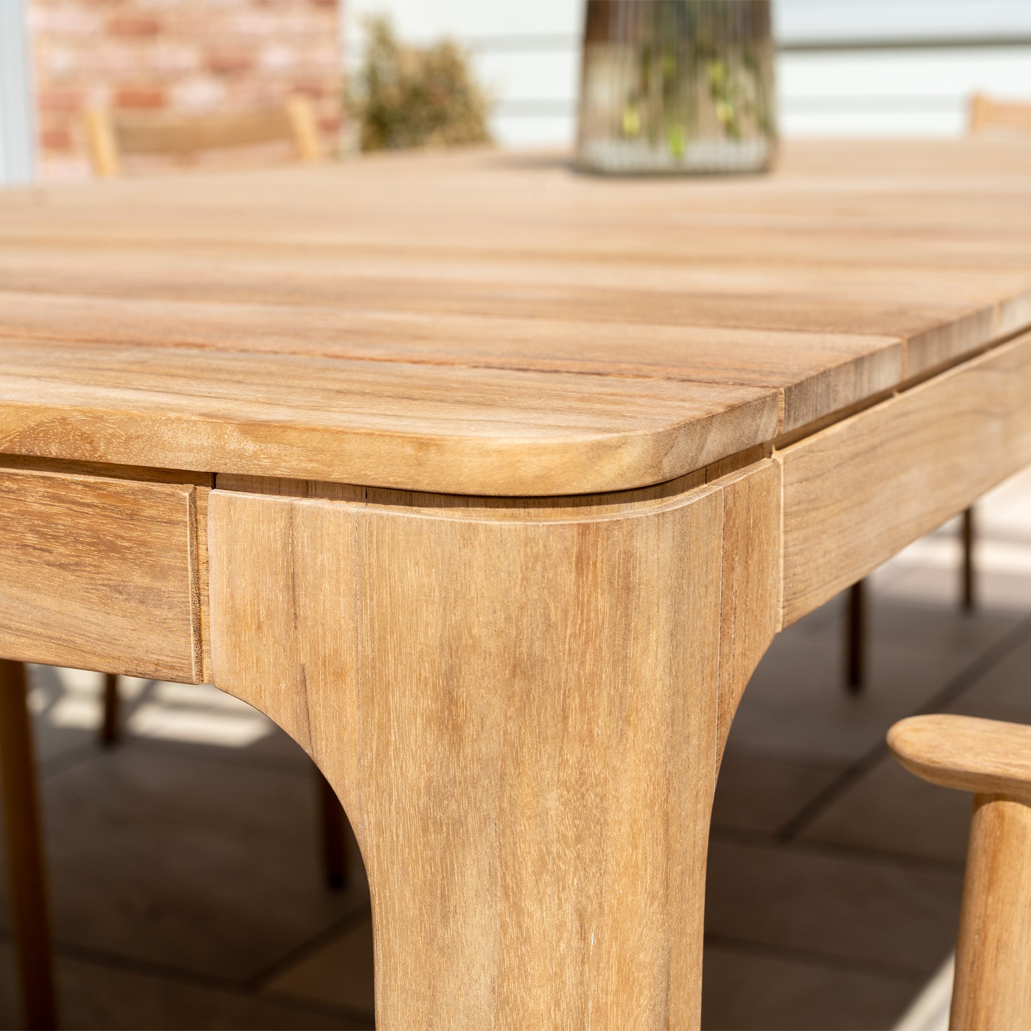 Close-up of the teak table with smooth edges and natural finish from the Siena 8 Seat Dining Set with Teak Table in Fawn, shown on a patio.