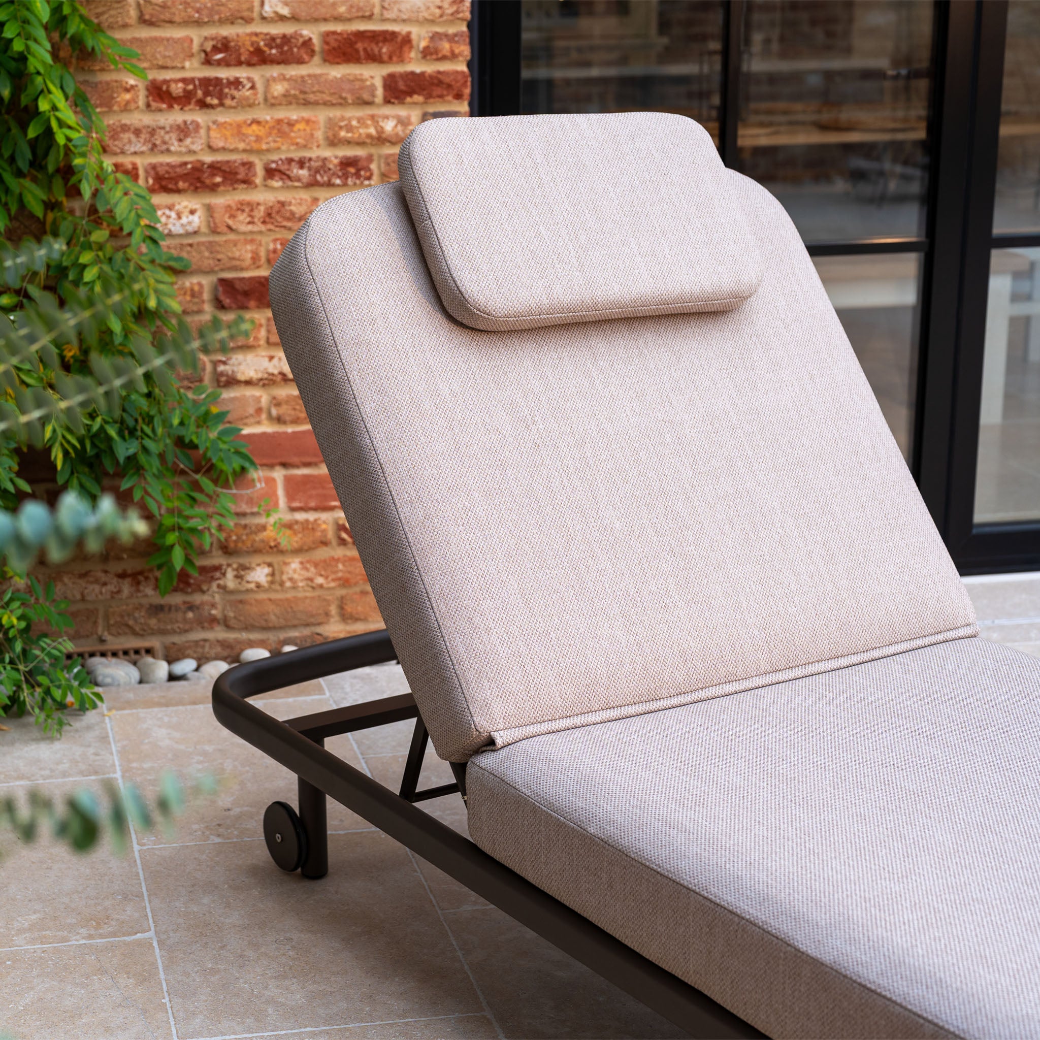 Enjoy the Sofia Sunlounger with Headrest and Wheels in Putty on your patio—perfect for relaxing outdoors in style.