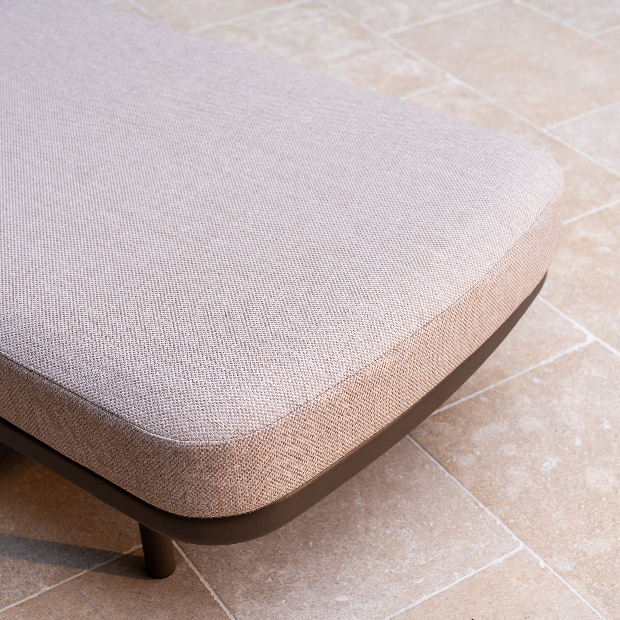 Close-up of the Sofia Sunlounger with Headrest and Wheels in Putty on a tiled floor, offering comfortable seating inspired by outdoor lounging.