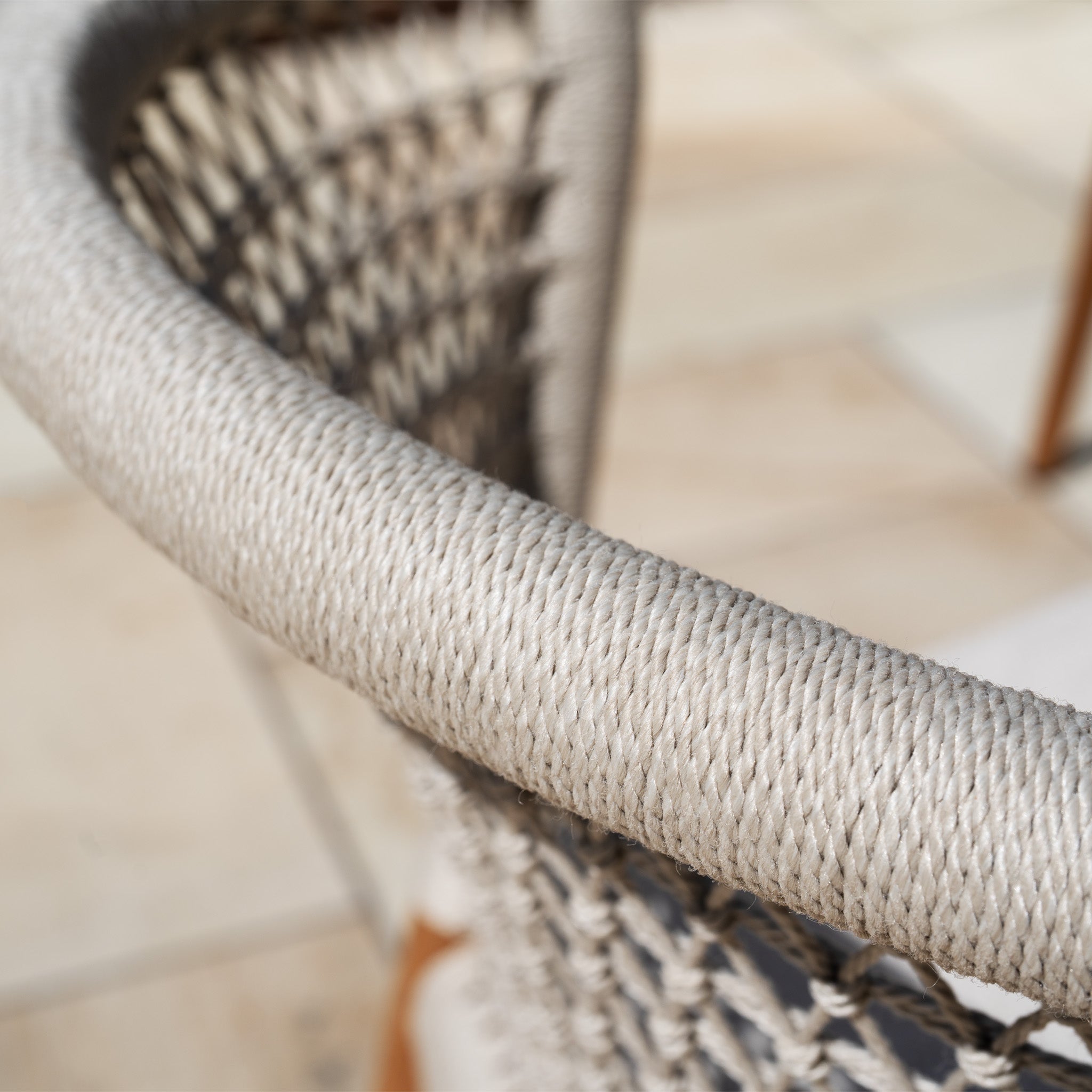 Close-up of the Sora 8 Seat Rope Dining Set with Teak Table in Stone, showing the woven rope chair backrest in soft natural light and neutral tones.
