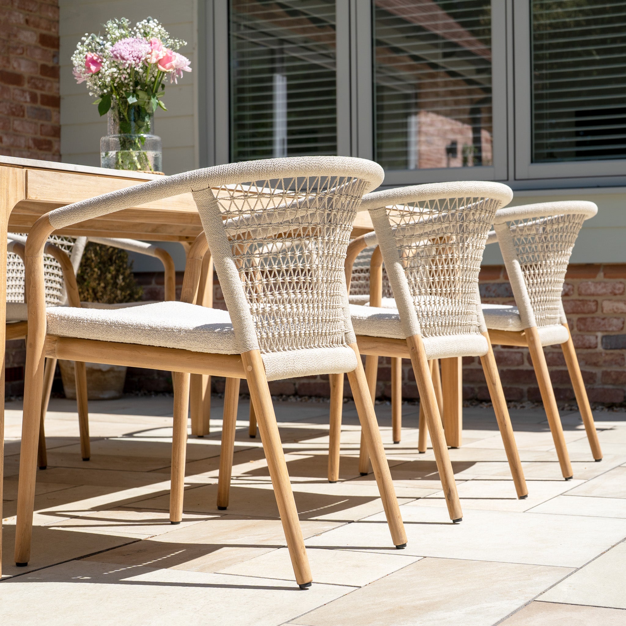 The Sora 8 Seat Rope Dining Set with Ceramic Top Table in Stone offers stylish outdoor seating, perfect for relaxing on a sunny patio and enjoying meals with family or friends.