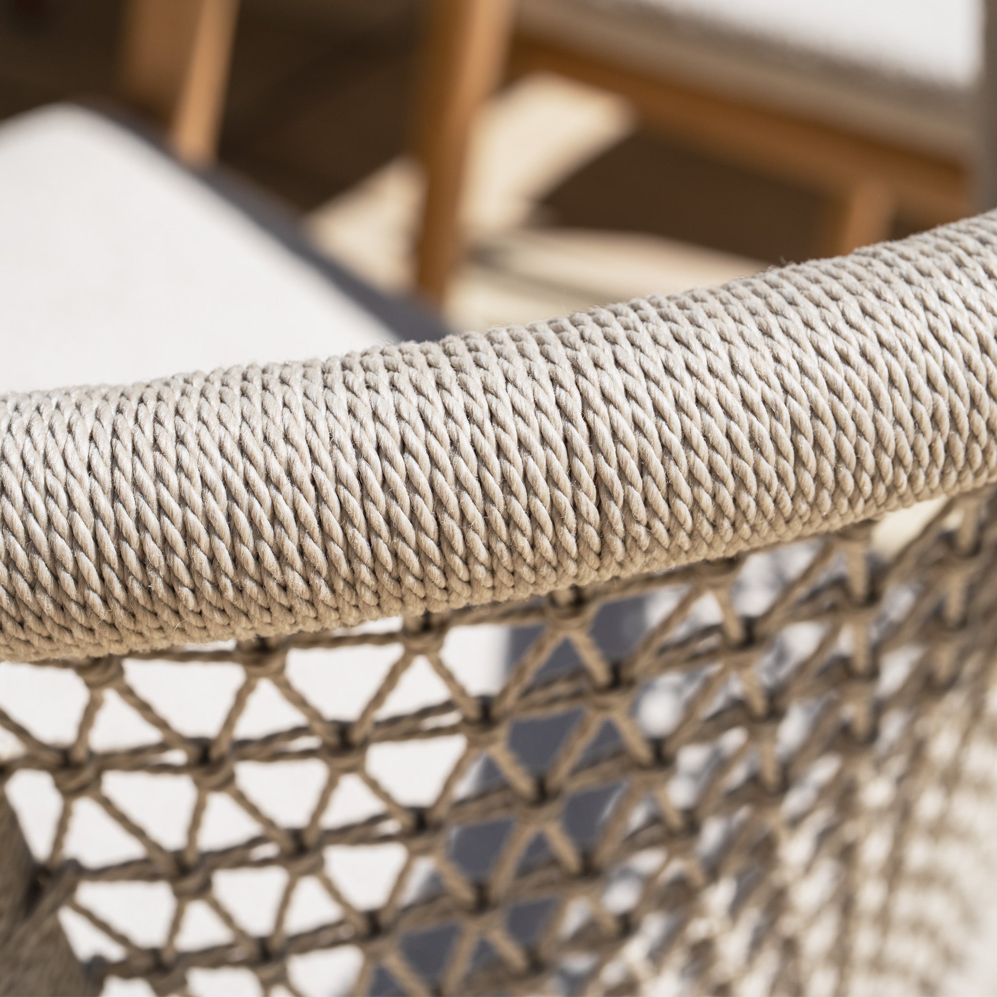 Close-up of the woven rope backrest on the Sora 8 Seat Rope Dining Set, highlighting its beige crisscross pattern in bright sunlight with a ceramic top table in stone.