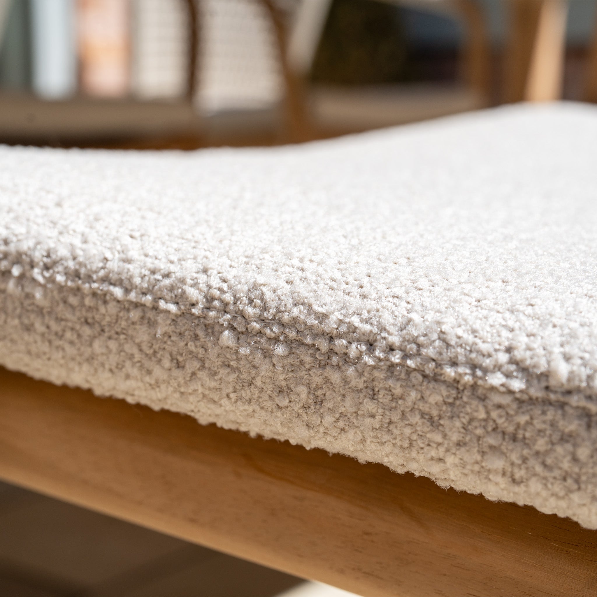 Close-up of a light beige textured cushion on the Sora 8 Seat Rope Dining Set with Ceramic Top Table in Stone, set on a teak chair with a blurred background.