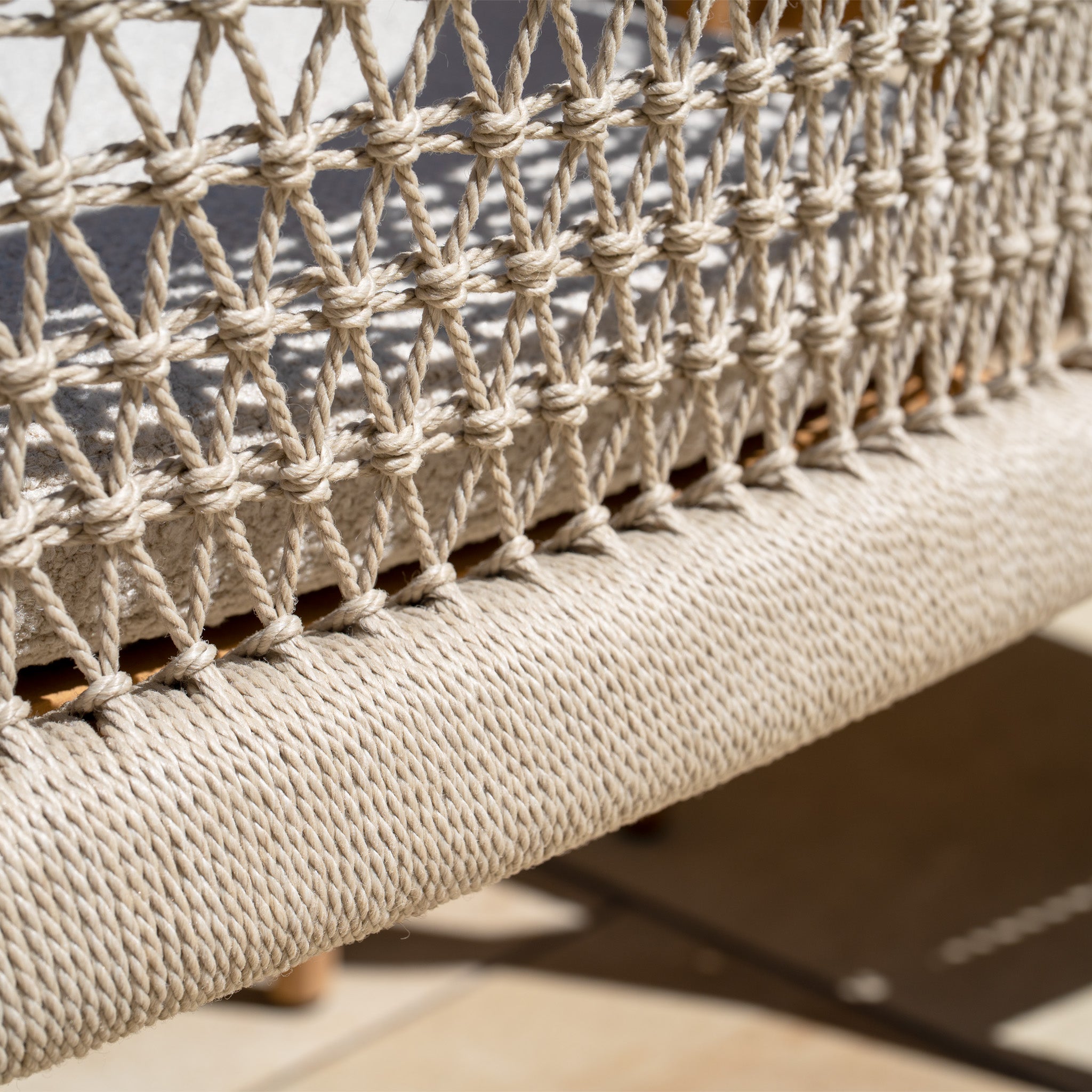 Close-up of the beige woven rope pattern on a Sora 8 Seat Rope Dining Set with Ceramic Top Table in Stone, glowing in the sunlight.