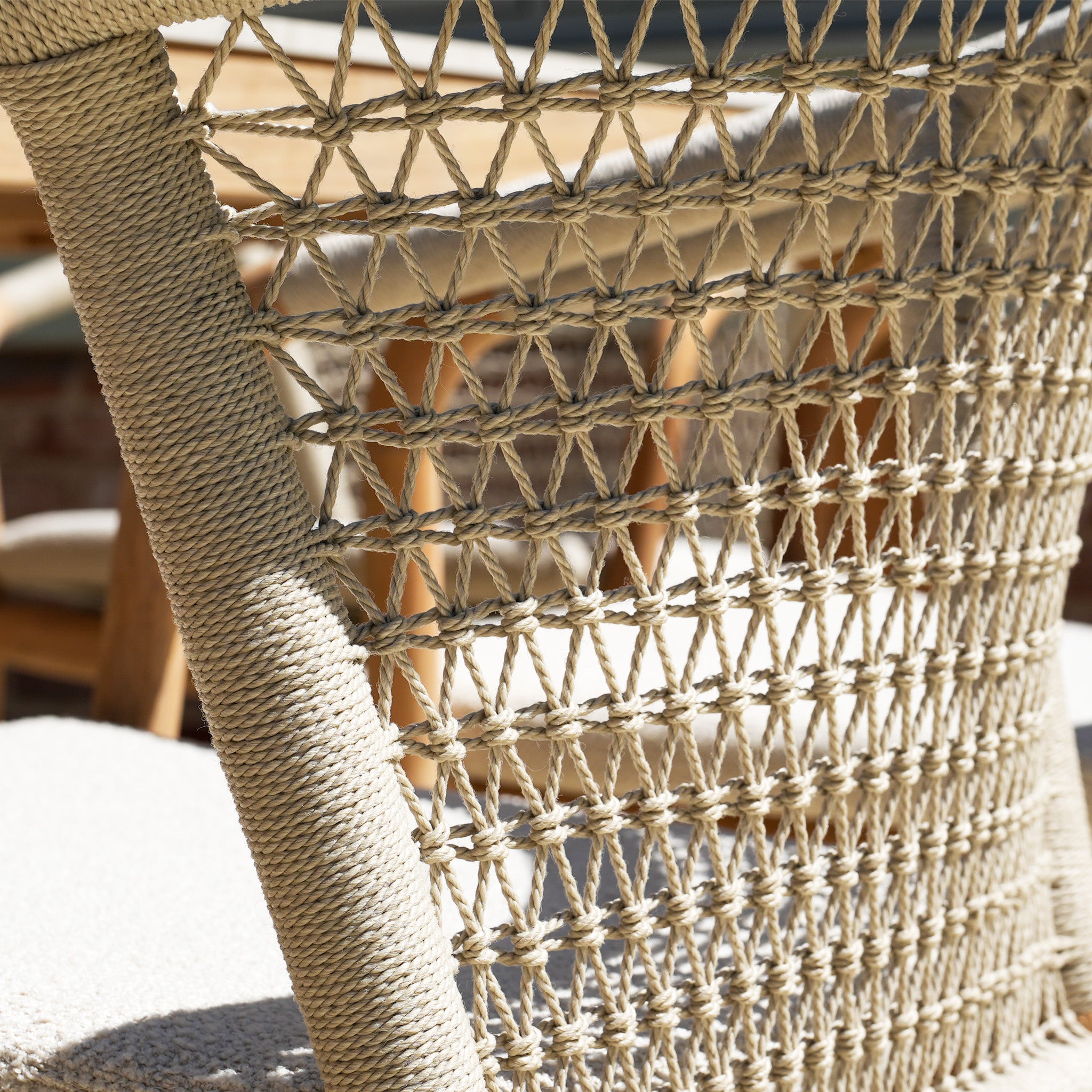 Close-up of the woven rope backrest on a Sora 8 Seat Rope Dining Set chair with sunlight creating shadows, and the ceramic top table in Stone visible in the background.