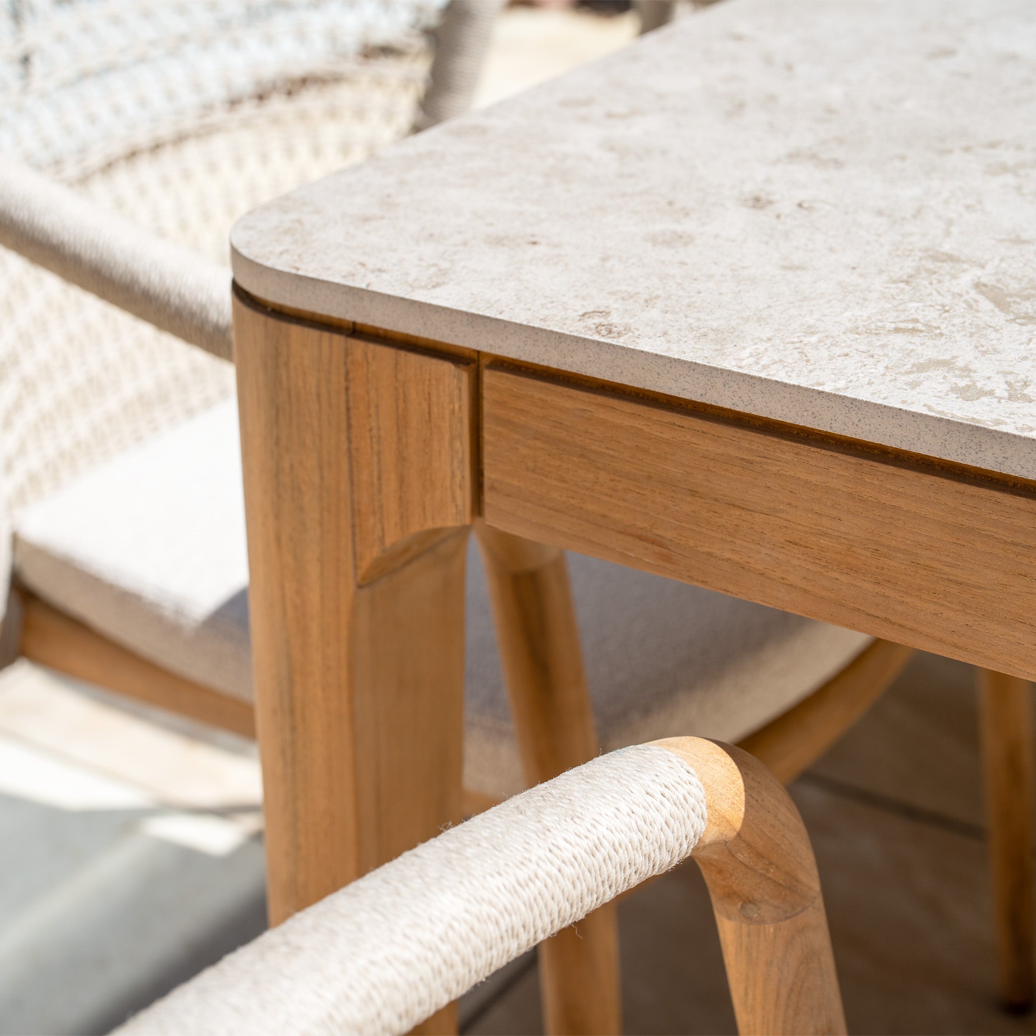 Close-up of the Sora 8 Seat Rope Dining Set with a stone ceramic top table and chairs featuring light handwoven rope armrests.