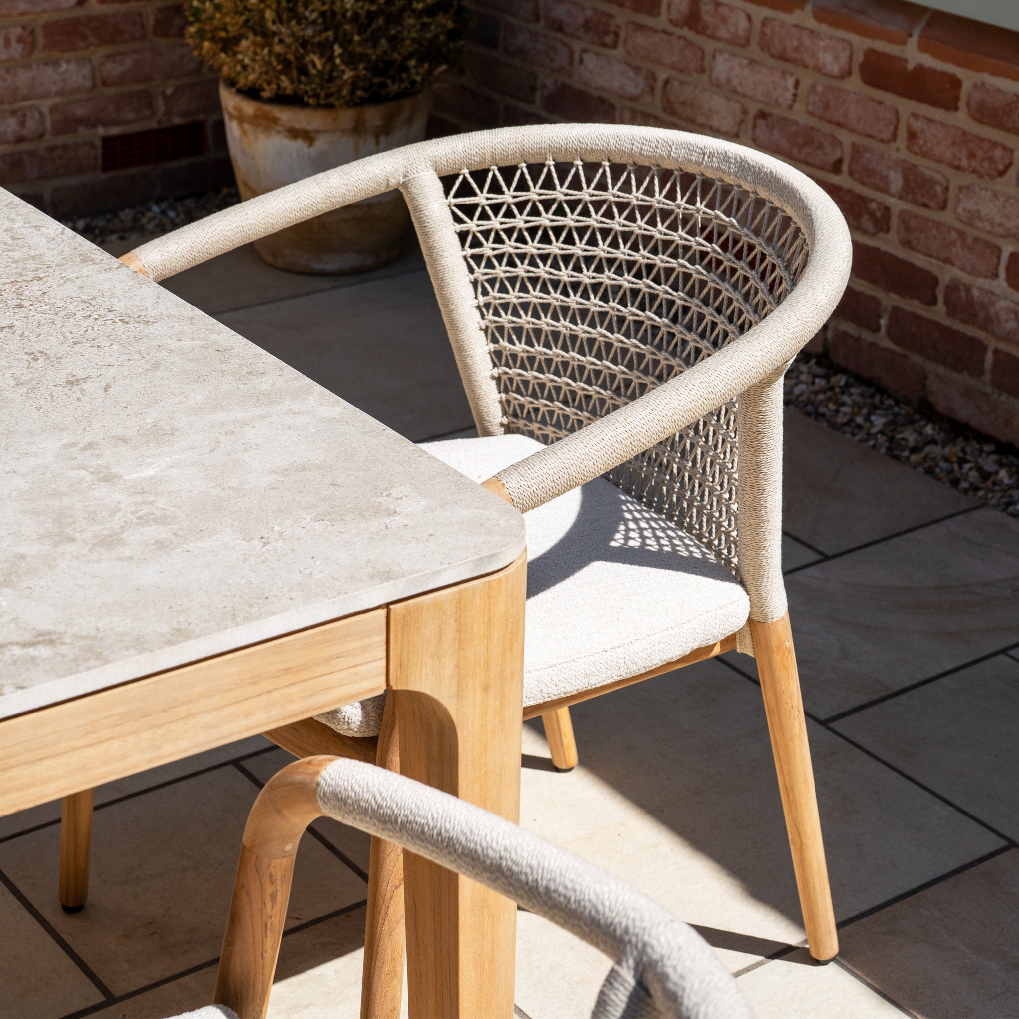 The Sora 8 Seat Rope Dining Set with Ceramic Top Table in Stone features handwoven rope chairs and a light ceramic-topped table, bringing modern style to your patio.