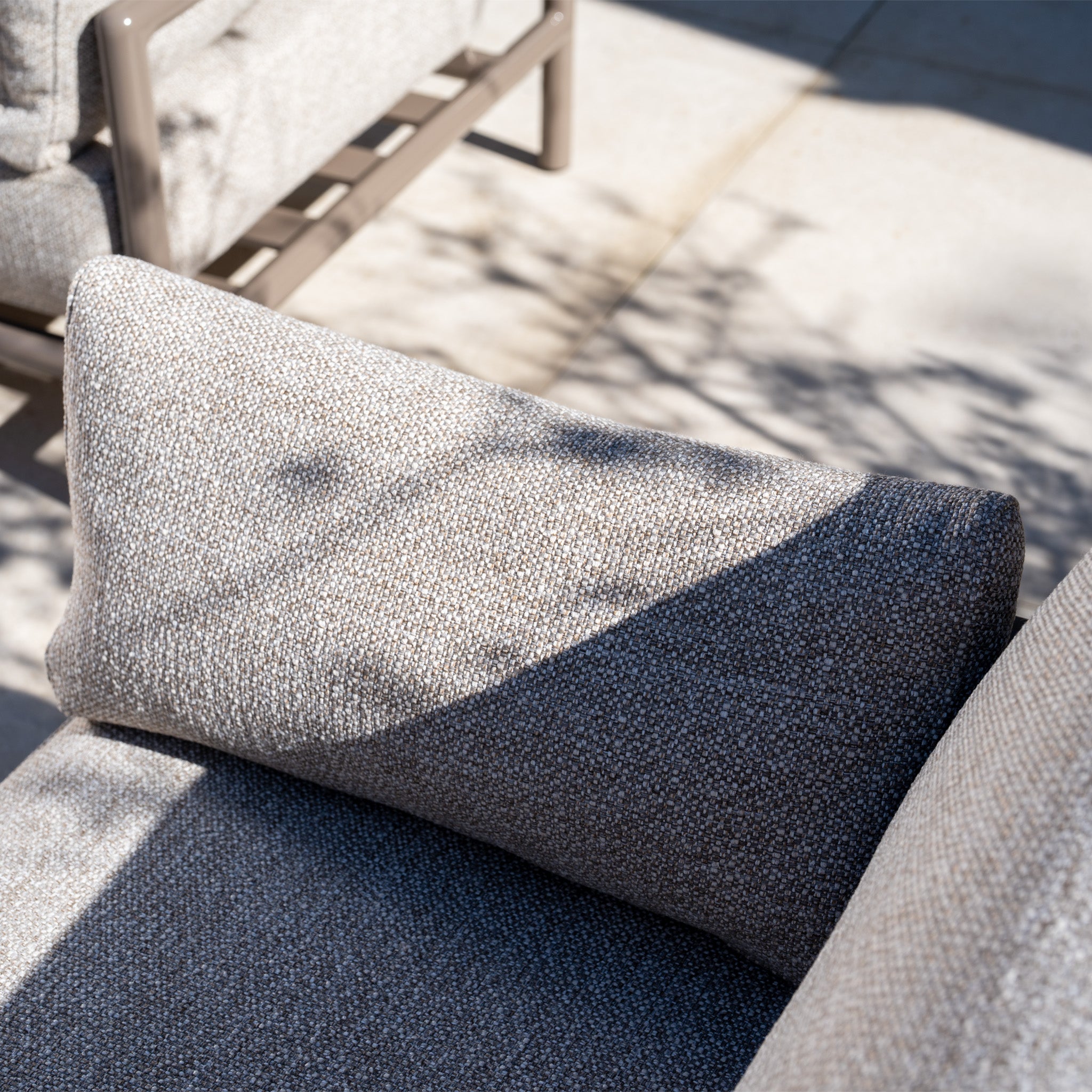 Close-up of a textured cushion on the Sorelli 2 Seat Sofa Set in Oatmeal, with dappled sunlight from nearby branches highlighting its detail on a sunny day.