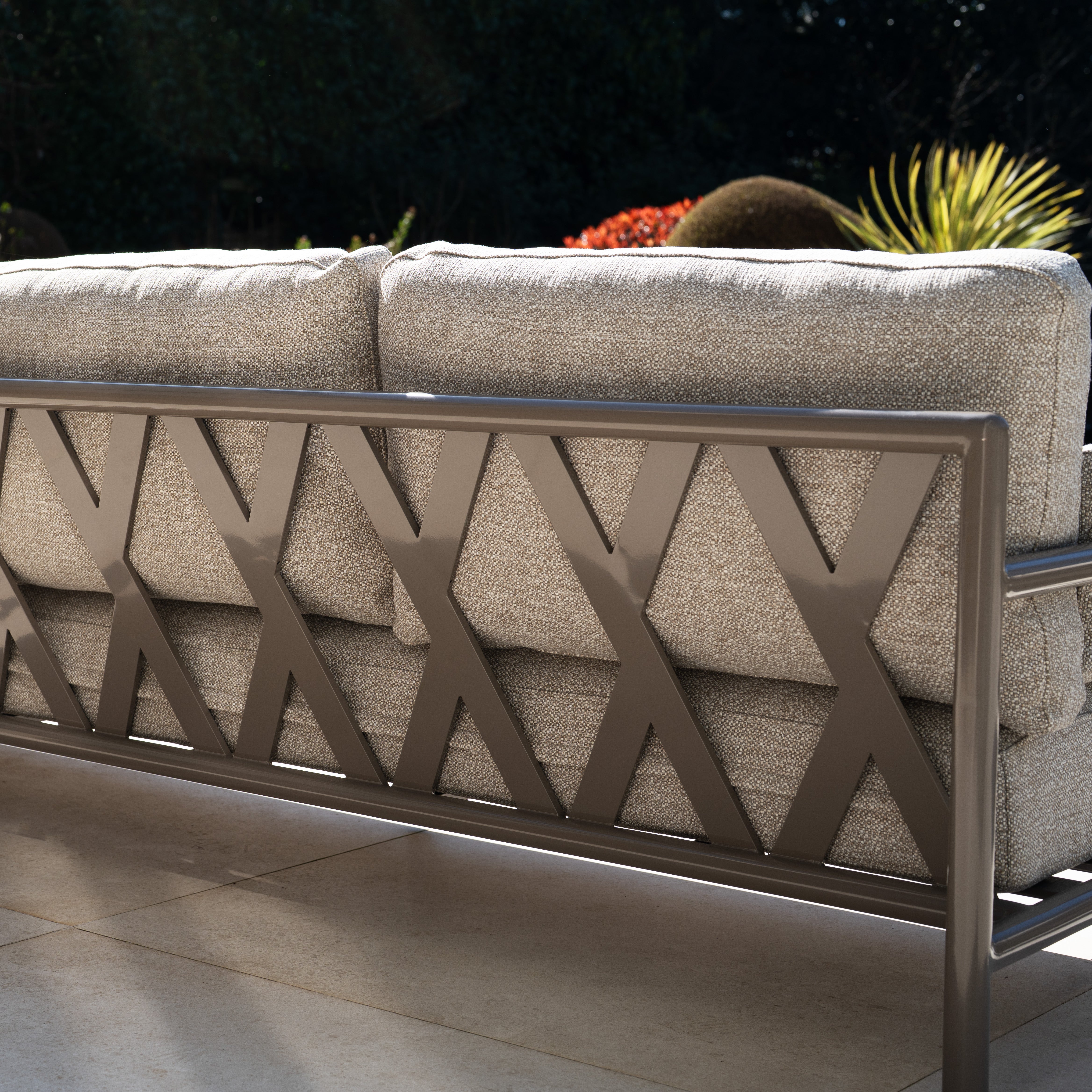 The Sorelli 2 Seat Sofa Set in Oatmeal features beige cushions and a metal backrest with a crisscross "X" design. This weather-resistant garden furniture is perfect for patios, blending comfort and durability.