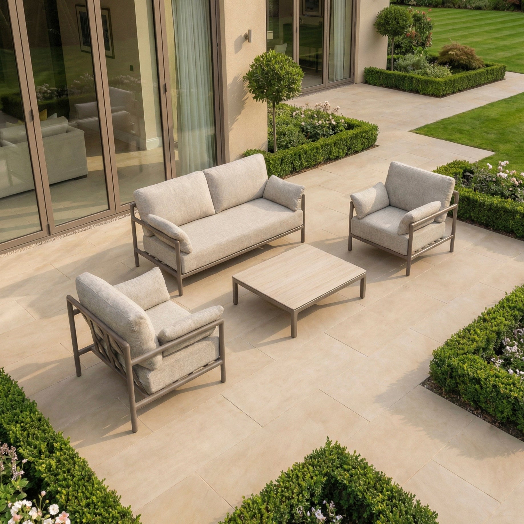 Enhance your patio with the Sorelli 2 Seat Sofa Set in Oatmeal, featuring two chairs and a table. This weather-resistant set adds lasting comfort and style to your garden or terrace, perfect for relaxing by manicured bushes.
