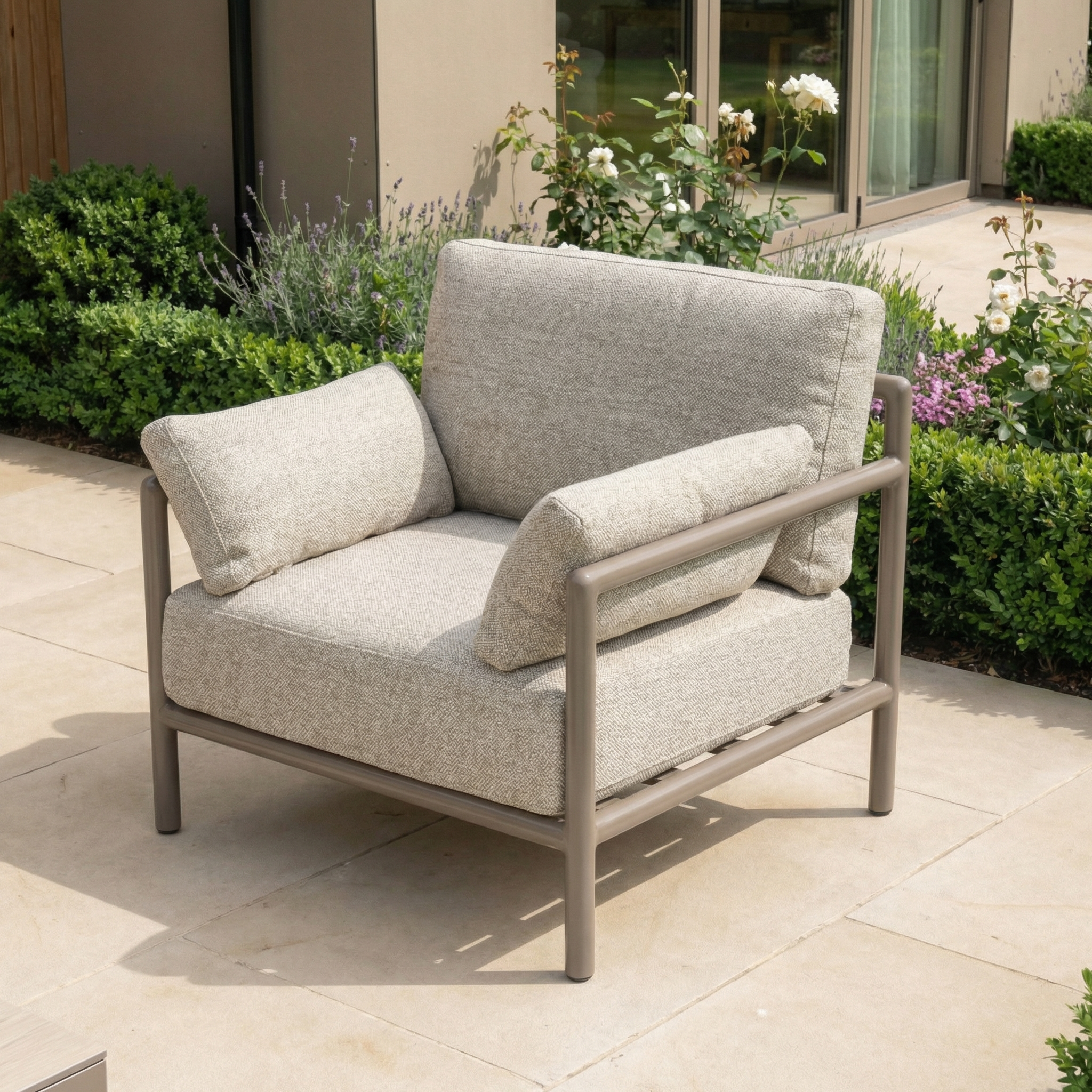 The Sorelli Armchair in Oatmeal is a weather-resistant garden chair with soft cushions and a sturdy metal frame, ideal for relaxing on your patio surrounded by greenery and flowers.