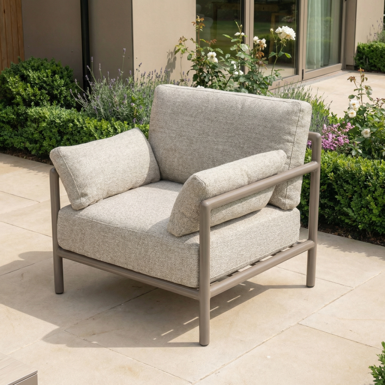 The Sorelli Armchair in Oatmeal is a weather-resistant garden chair with soft cushions and a sturdy metal frame, ideal for relaxing on your patio surrounded by greenery and flowers.