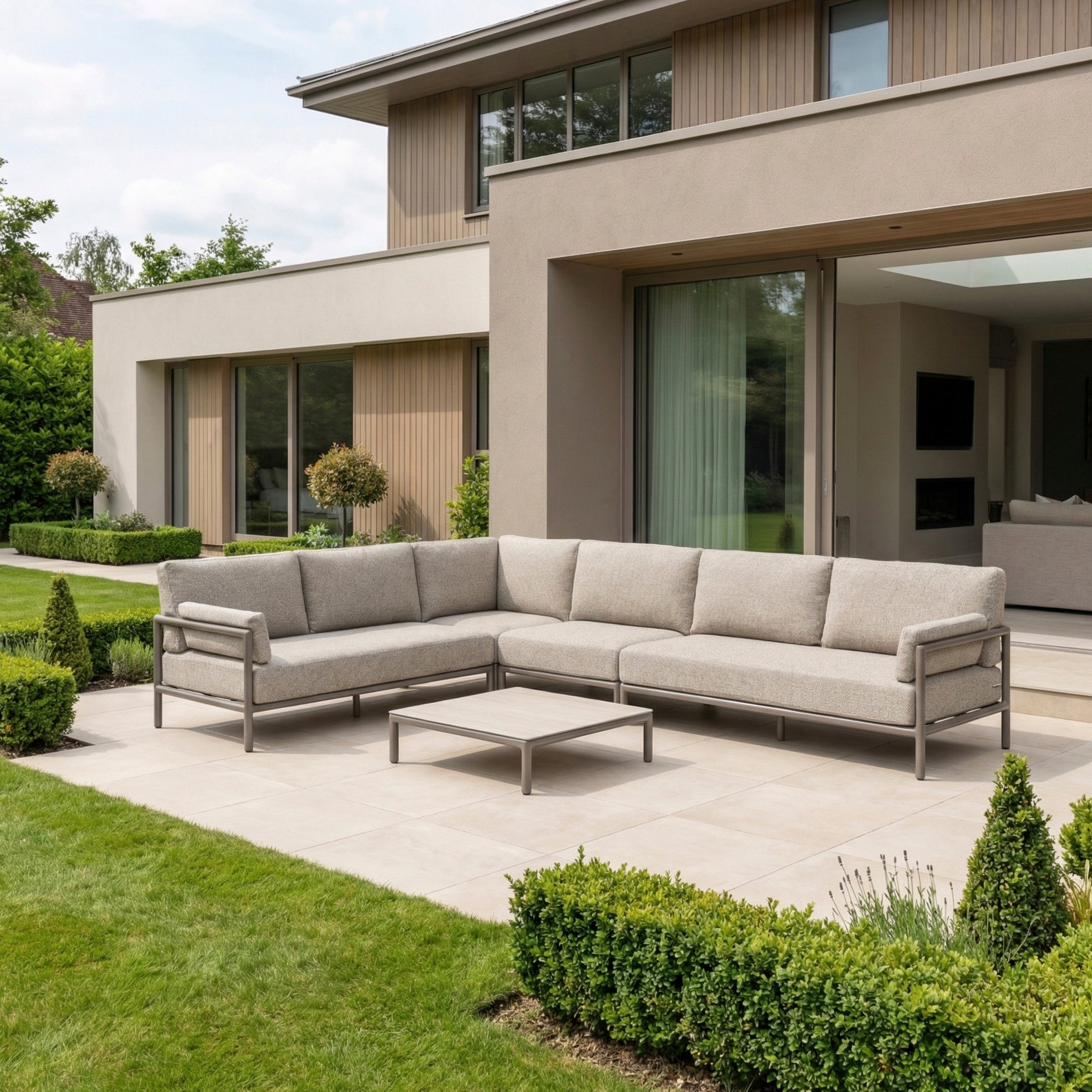 Modern patio with a Sorelli Corner Sofa Set in Oatmeal, featuring an aluminium frame and a low table—perfectly complementing the contemporary house.