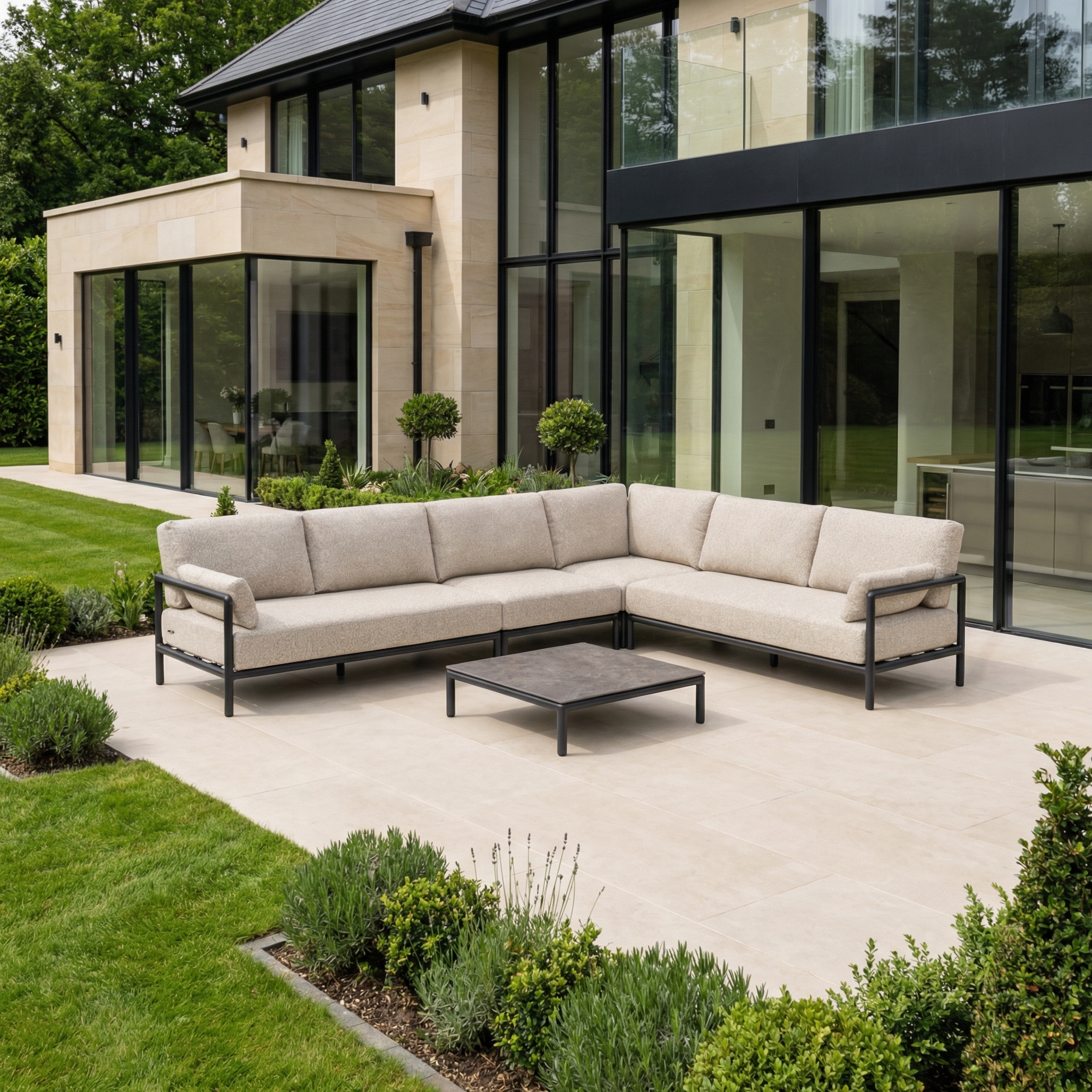 Modern patio featuring the Sorelli Corner Sofa Set in Truffle and a square coffee table outside a glass house, highlighting stylish garden furniture.