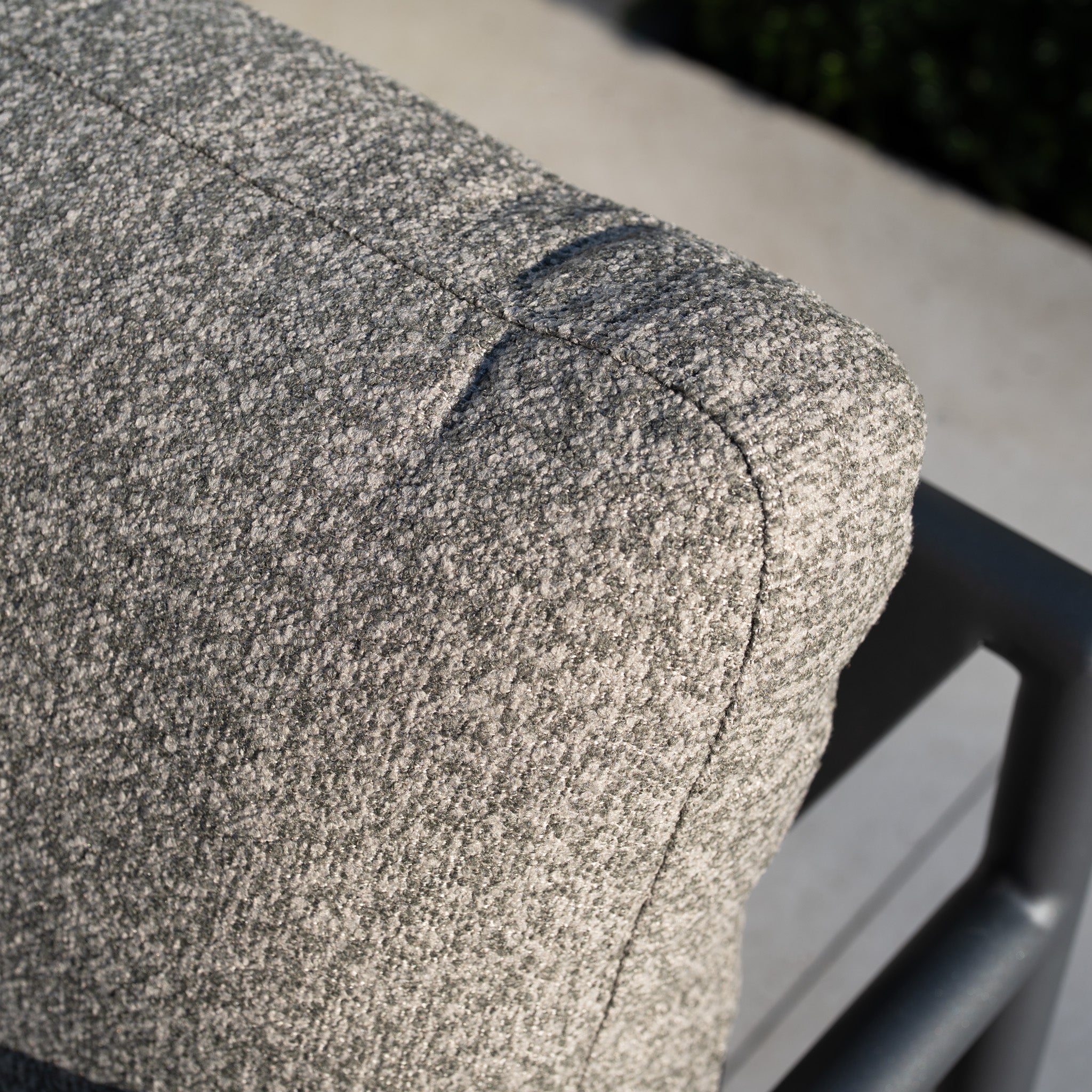 Close-up of a textured gray outdoor cushion on a metal chair, sunlight casting shadows—ideal for elevating your garden look or pairing with the Sorelli Corner Sofa Set in Truffle.