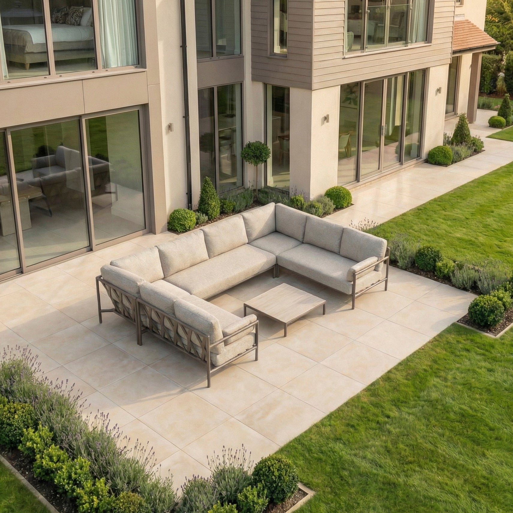 Modern patio with the Sorelli U Shape Corner Sofa Set in Oatmeal and table, arranged on tiled flooring beside a landscaped garden.