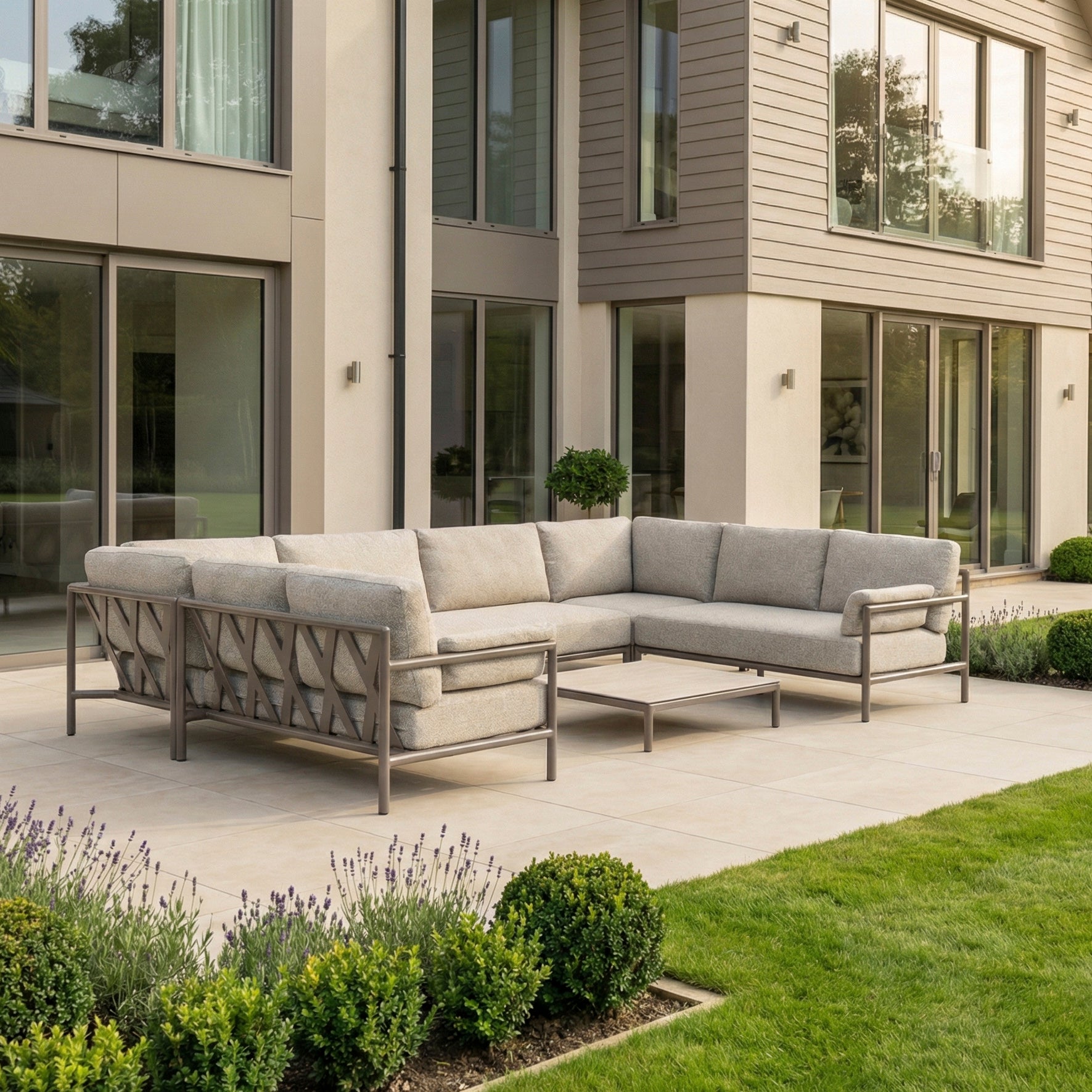 The Sorelli U Shape Corner Sofa Set in Oatmeal features an aluminum frame and table, stylishly arranged on a patio outside a modern house with large windows.