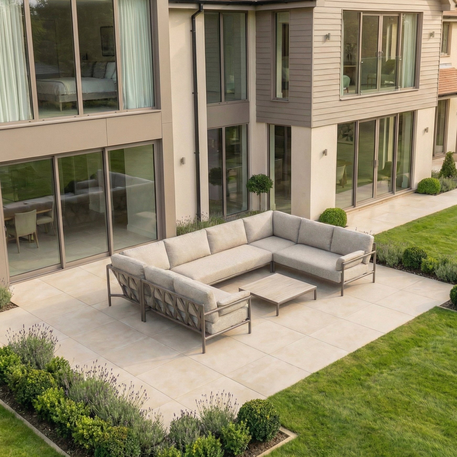 Modern patio with the Sorelli U Shape Corner Sofa Set in Oatmeal and a coffee table on a tiled terrace beside a contemporary house.