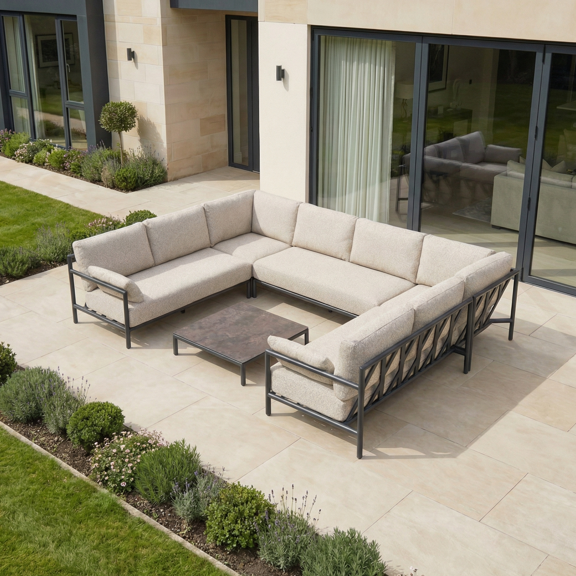 Outdoor patio with the Sorelli U Shape Corner Sofa Set in Truffle, featuring weather-resistant cushions and a low table, set before a landscaped garden—ideal for stylish outdoor entertaining.