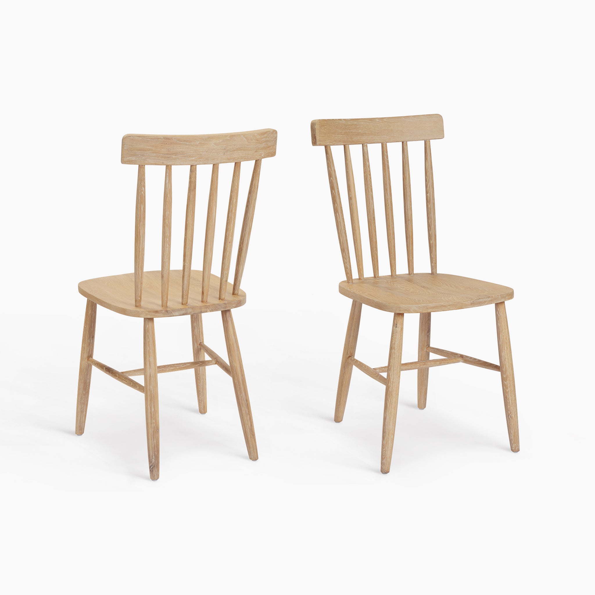 The Burford Set of 2 Spindleback Dining Chairs in Natural Oak features elegant curved backs and a light natural finish, perfect as stylish oak dining chairs for any modern dining space.