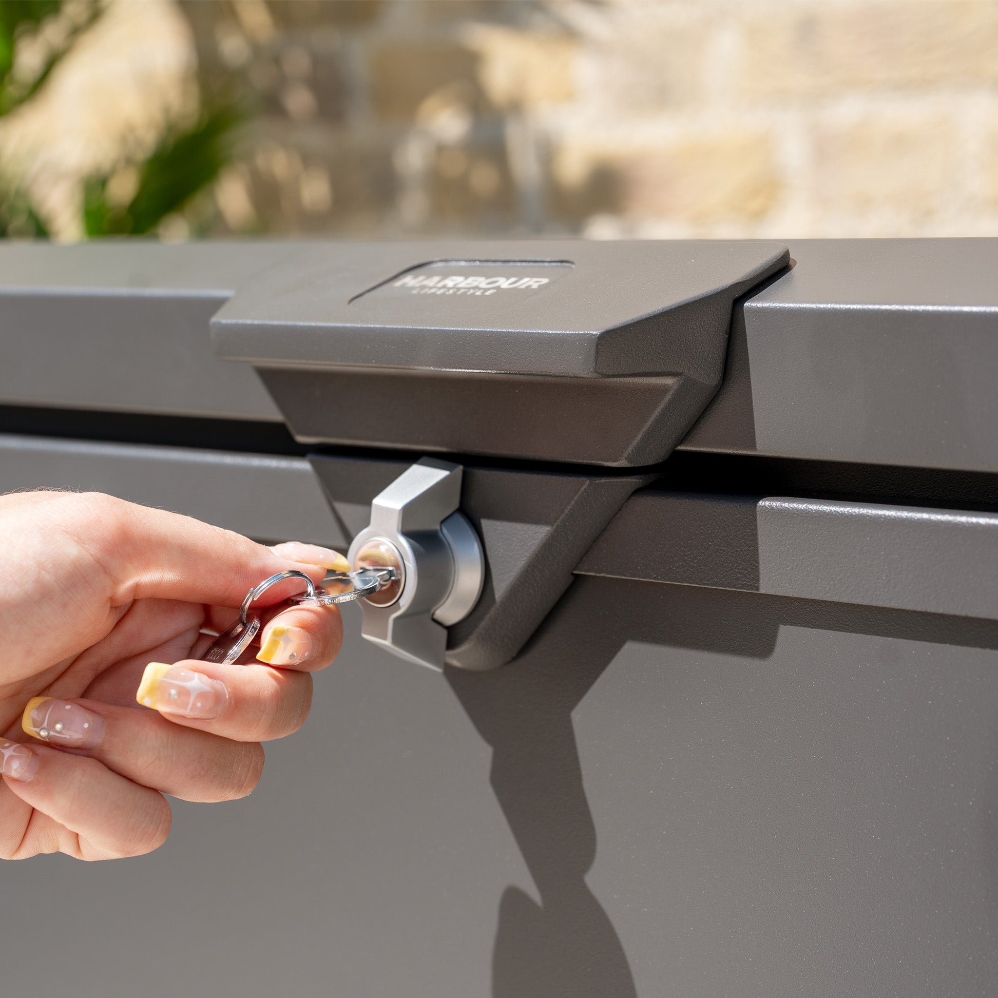 A hand is locking the Small Steel Storage Box in Grey with a key.