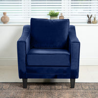 A Wiltshire Velvet Armchair in Royal Blue, made from FSC-certified wood, sits by a window with blinds and is accompanied by small decorative items.