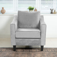 The Wiltshire Velvet Armchair in Feather Grey, with its square design, sits in front of the window beautifully adorned with plants and small sculptures on the sill.