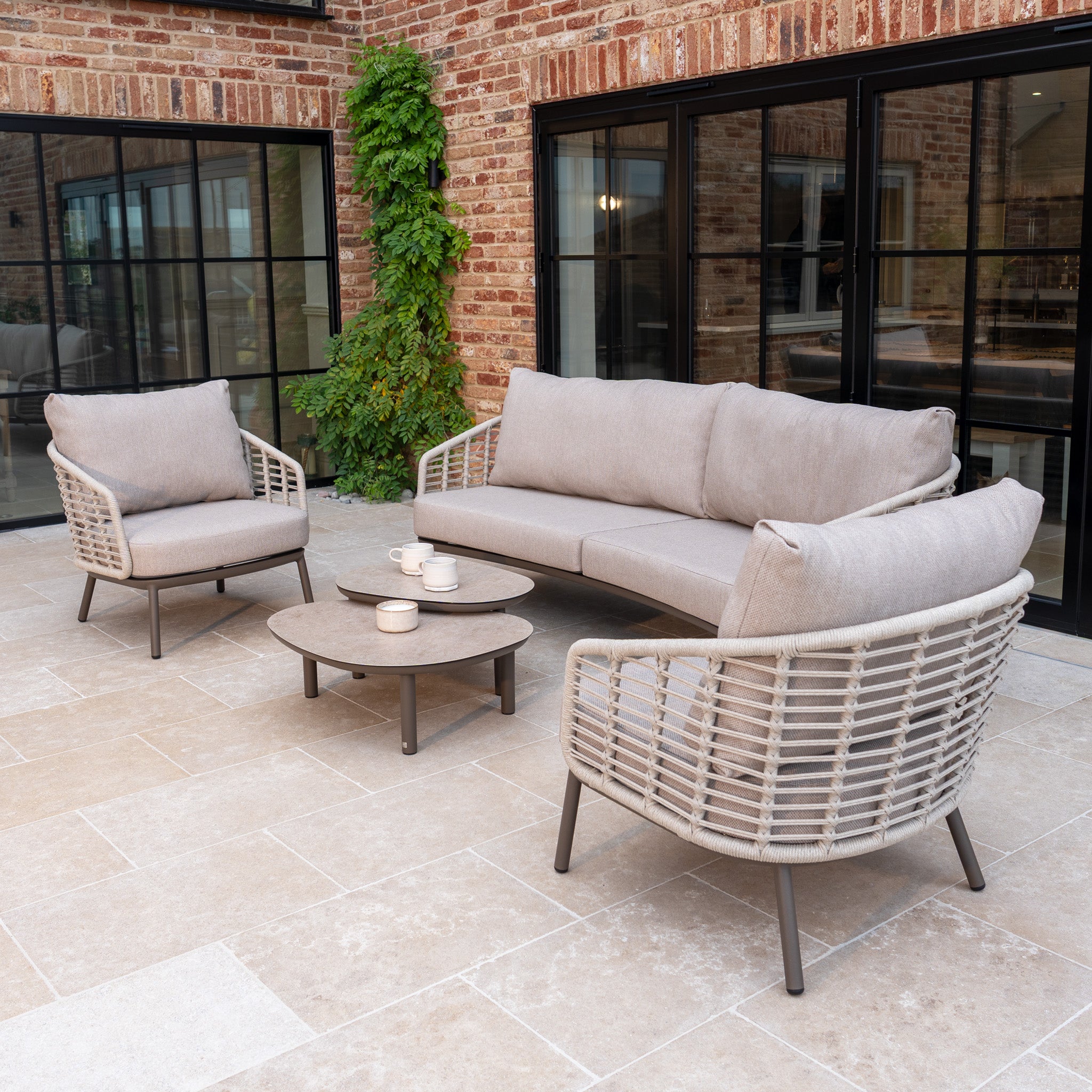 The Sutera 3 Seat Sofa Set in Putty features all-weather cushions, two chairs, and a coffee table—ideal for stylish outdoor living on your patio.