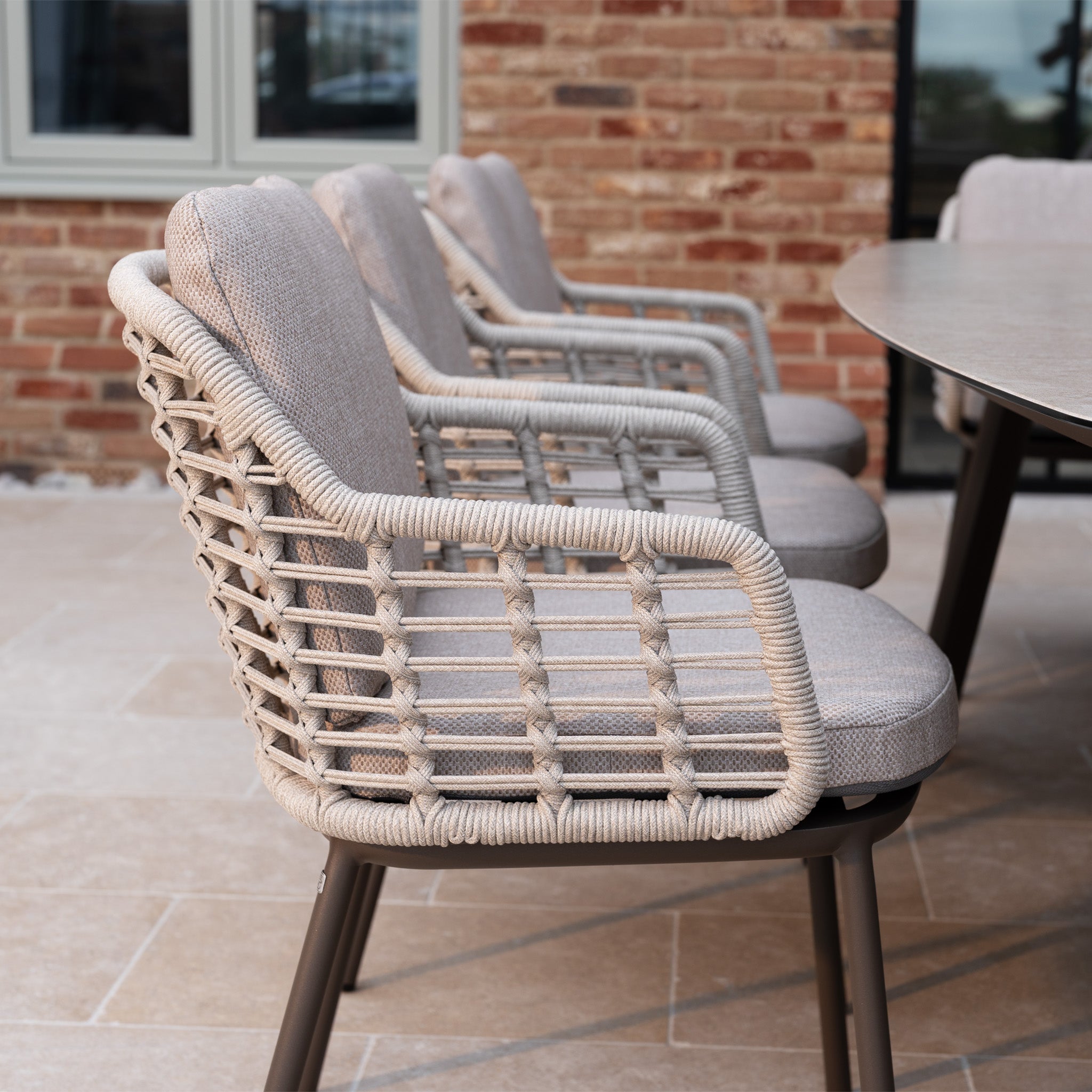 The Sutera 8 Seat Curved Rectangular Dining Set in Putty features stylish cushioned chairs and a spacious table, creating an inviting outdoor dining area ideal for gatherings on your patio.
