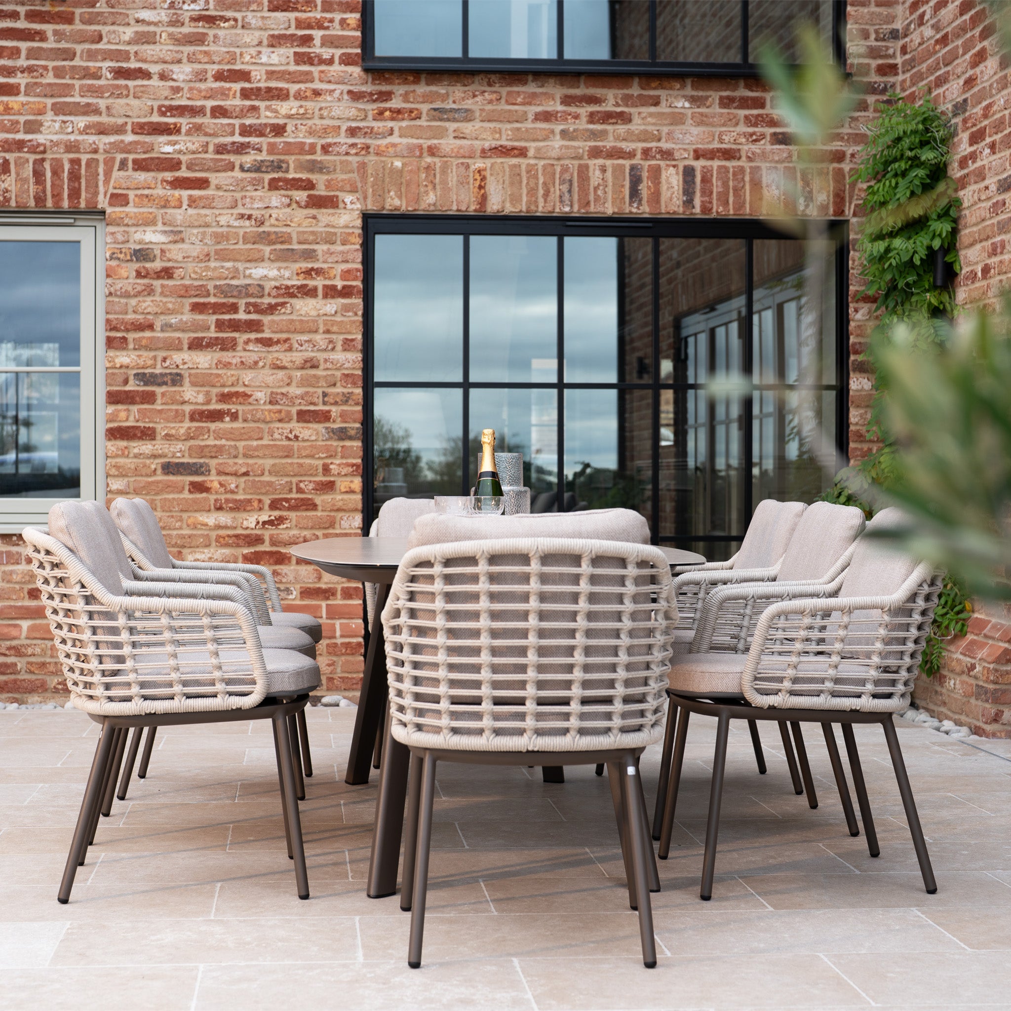 Enjoy outdoor dining with the Sutera 8 Seat Curved Rectangular Dining Set in Putty, featuring a stylish table and eight cushioned chairs for your patio.