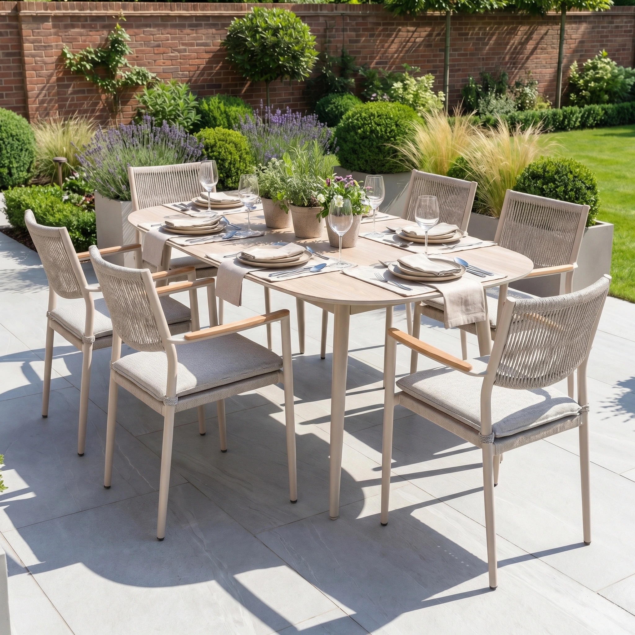 The Tellaro 6 Seat Oval Dining Set in Latte features a sintered stone table and stackable chairs for six, perfect for patios surrounded by lush green garden plants.