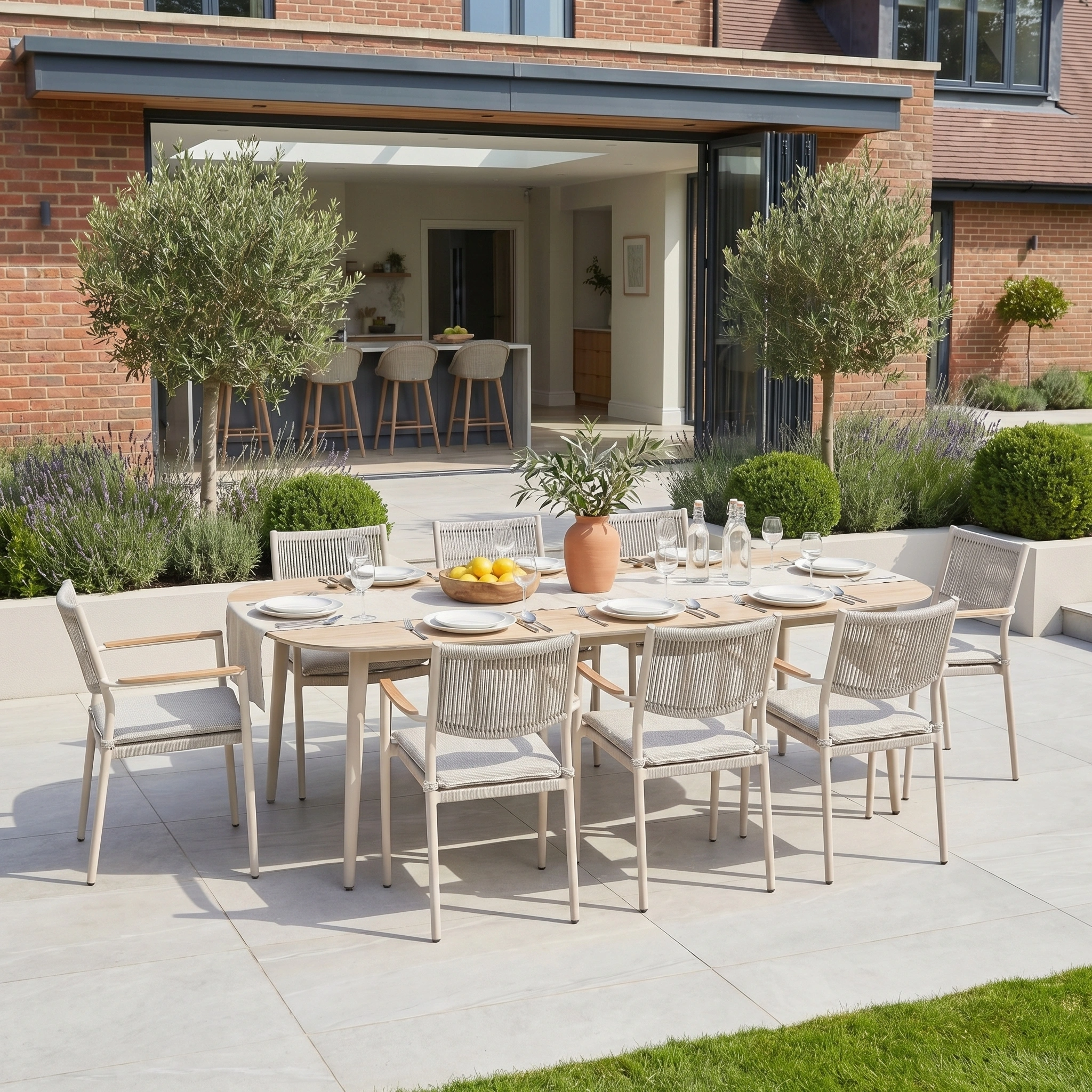 The Tellaro 8 Seat Oval Dining Set in Latte, crafted from aluminium and teak, is arranged on a sunlit patio surrounded by greenery—ideal for stylish and durable open-air gatherings.