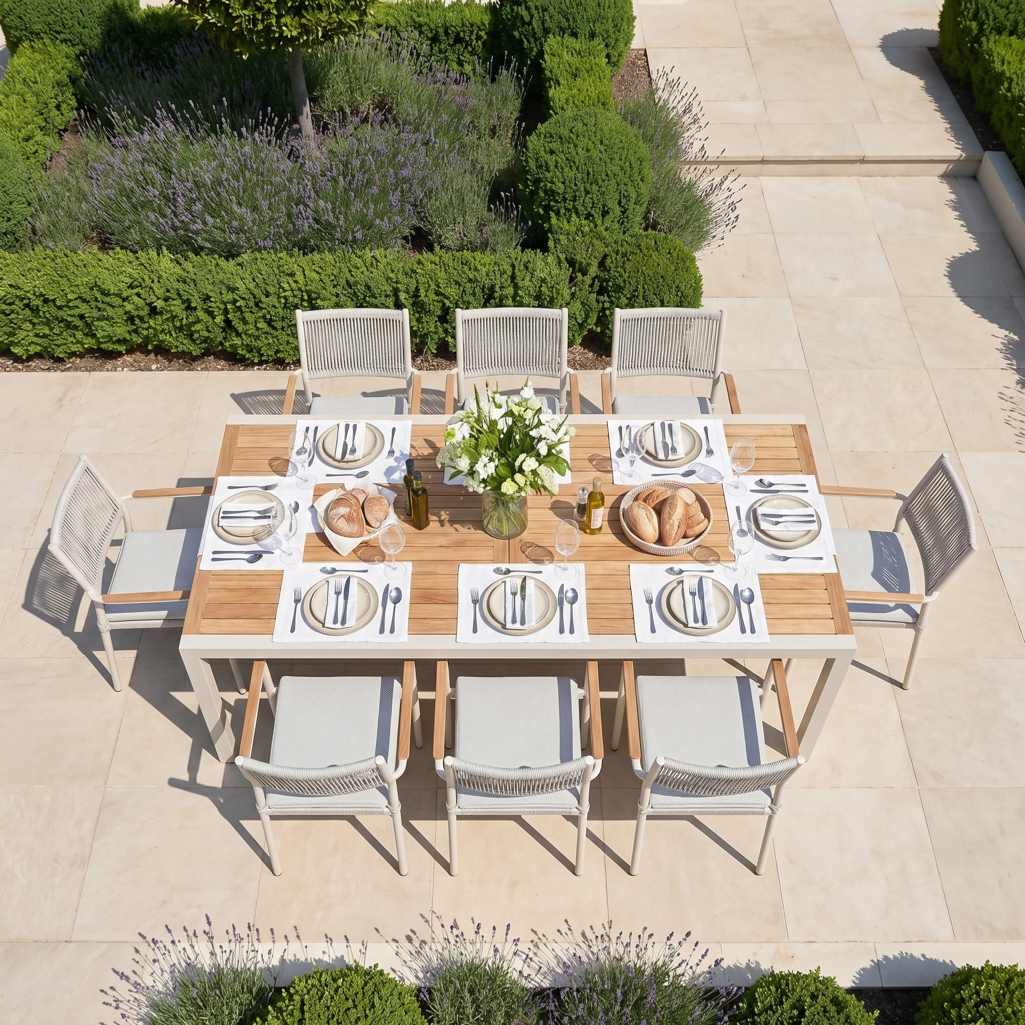 The Tellaro 8 Seat Extending Dining Set with Teak Table in Latte features a sturdy aluminium frame and is surrounded by lush garden greenery, with a table set for dining.