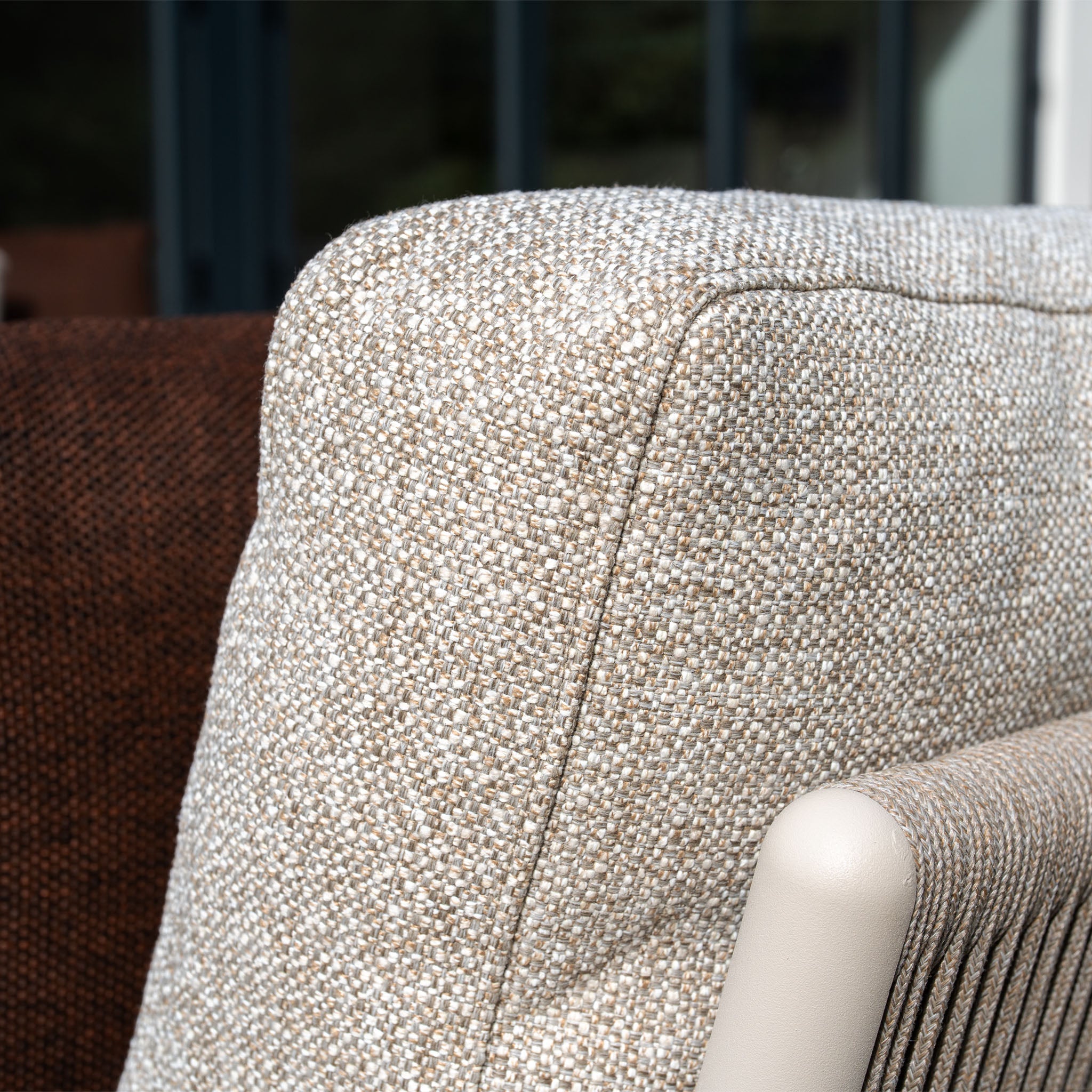 Close-up of a light beige textured cushion from Theia 3 Seat Sofa Set in Oatmeal, with part of a brown cushion and the chair arm visible.
