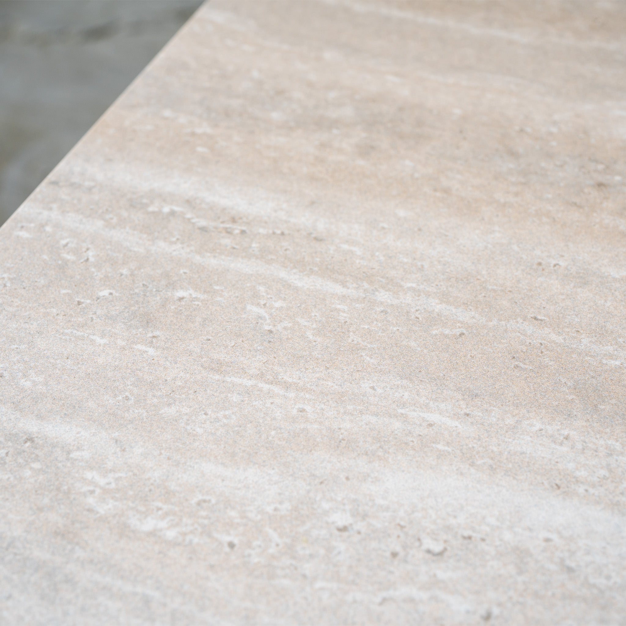 Close-up of a smooth, beige stone surface with subtle white and gray streaks and a matte finish—an elegant backdrop for modular garden furniture like the Theia 3 Seat Sofa Set in Oatmeal or a welcoming outdoor lounge area.