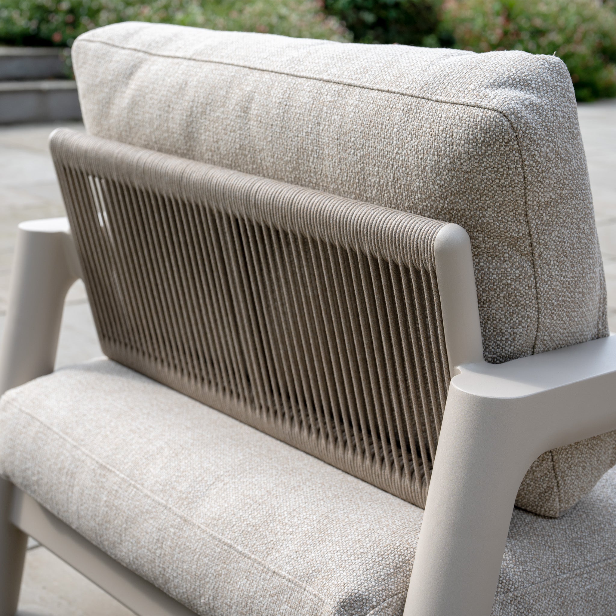 Close-up of the Theia 3 Seat Sofa Set in Oatmeal, showcasing its woven backrest and light beige cushions on a patio.