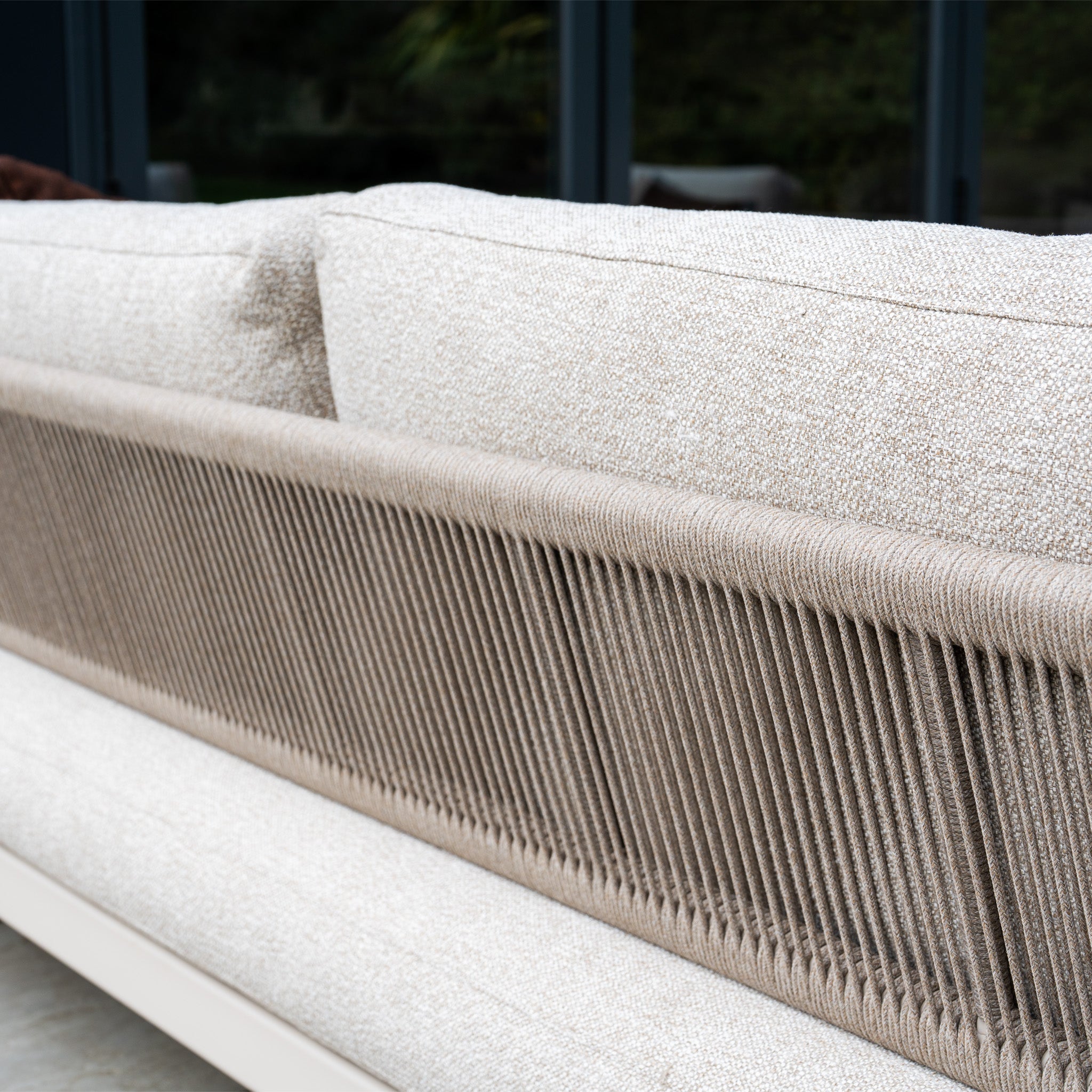 The Theia 3 Seat Sofa Set in Oatmeal features textured cushions and a decorative rope-wrapped backrest, offering a stylish modular garden seating option, shown here from behind.