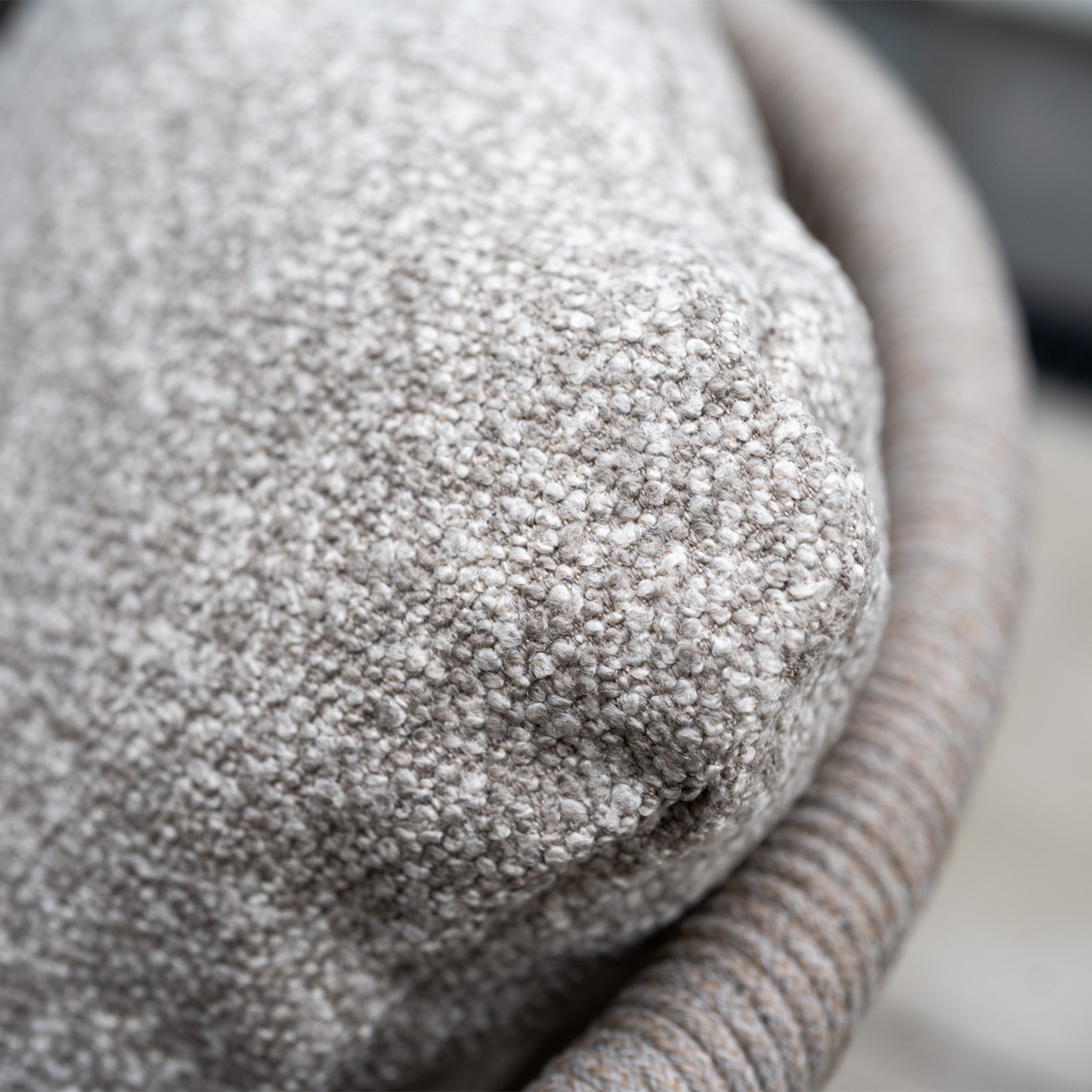 Close-up of a textured beige cushion on a woven chair from Theia 6 Seat Rope Dining Set with Albatross Extending Table in Oatmeal. Detailed fabric offers comfort and elegance, ideal for elevating any outdoor dining area.
