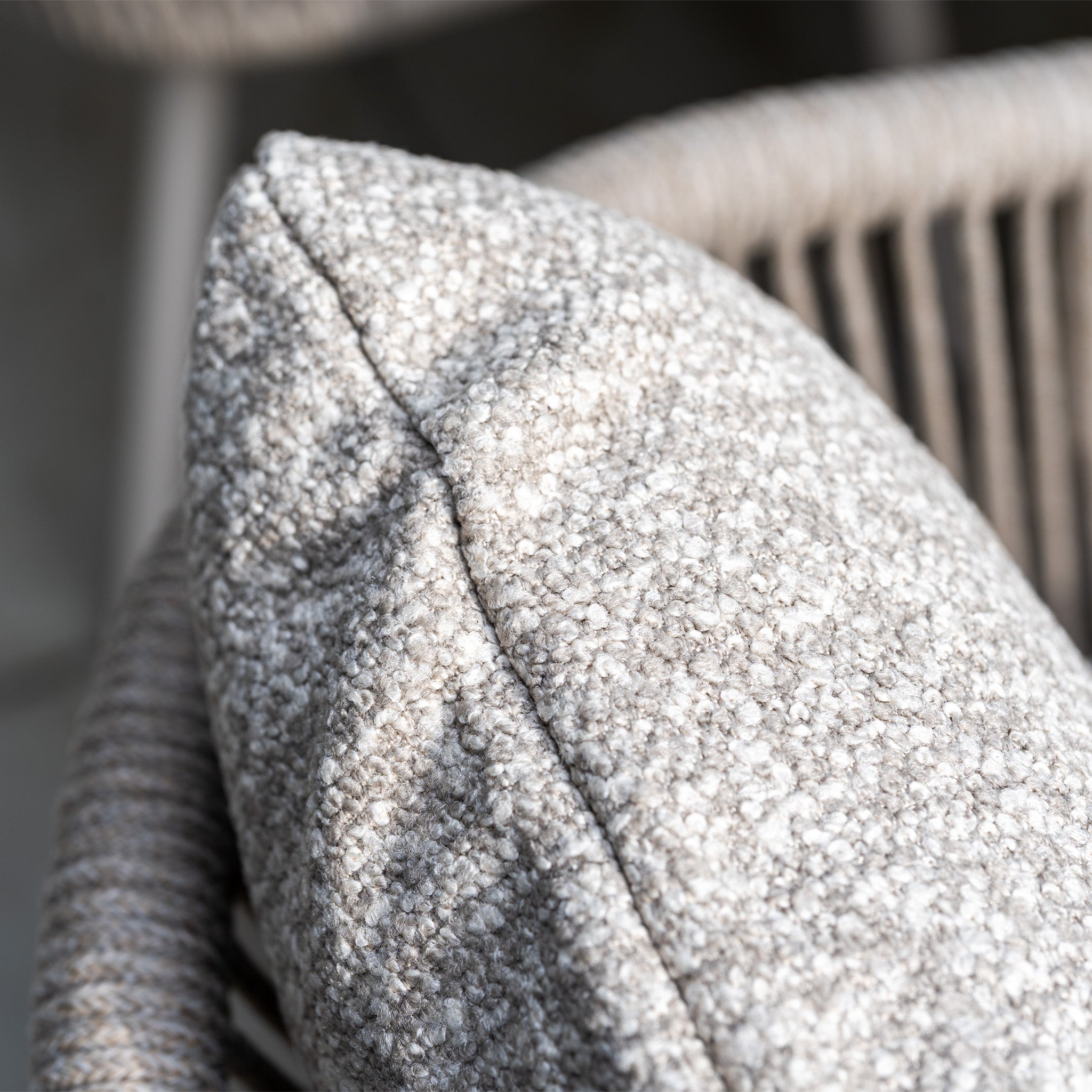 Close-up of a textured gray cushion on a woven chair, part of Theia 8 Seat Rope Dining Set with Albatross Extending Table in Oatmeal—an outdoor set ideal for gatherings.