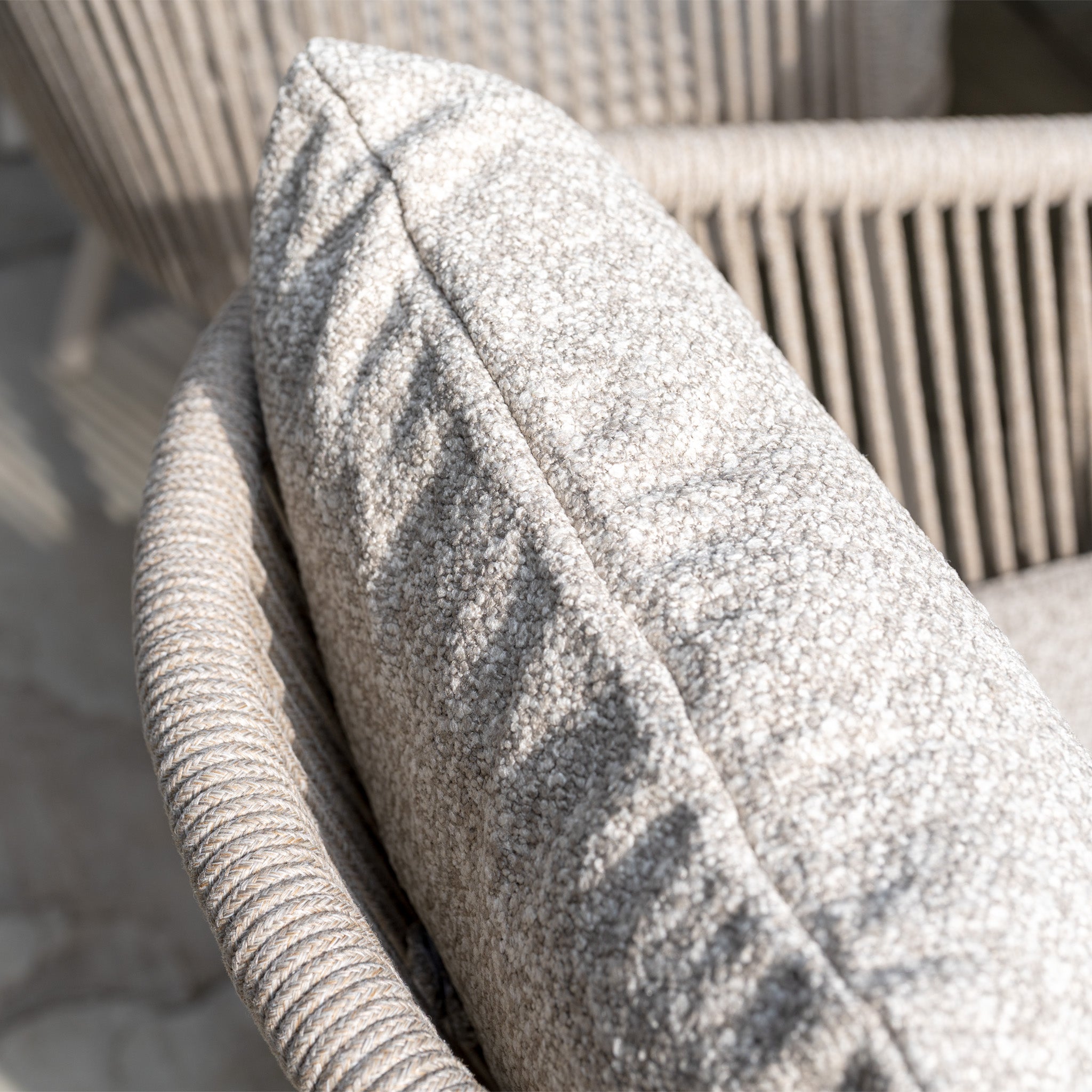 Close-up of a textured, light beige cushion on woven garden furniture from the Theia 8 Seat Oval Rope Dining Set with Albatross Extending Table in Oatmeal—ideal for relaxing outdoors as part of your dining set.