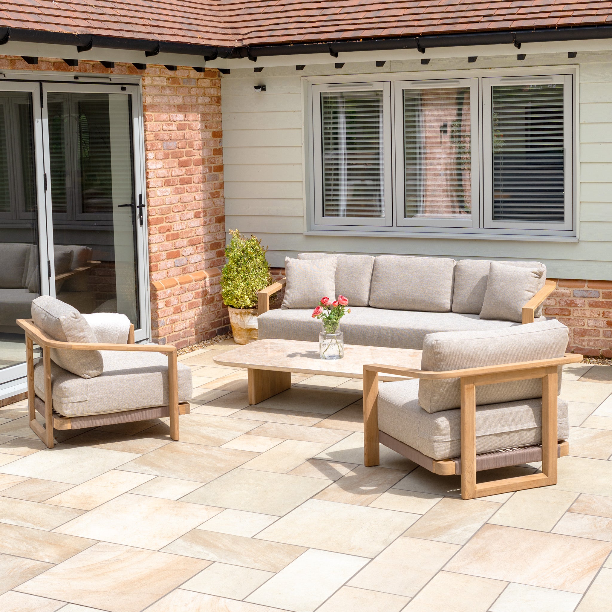 Modern outdoor patio set featuring the Tivoli 3 Seat Sofa Set with fawn cushions and a marble coffee table.