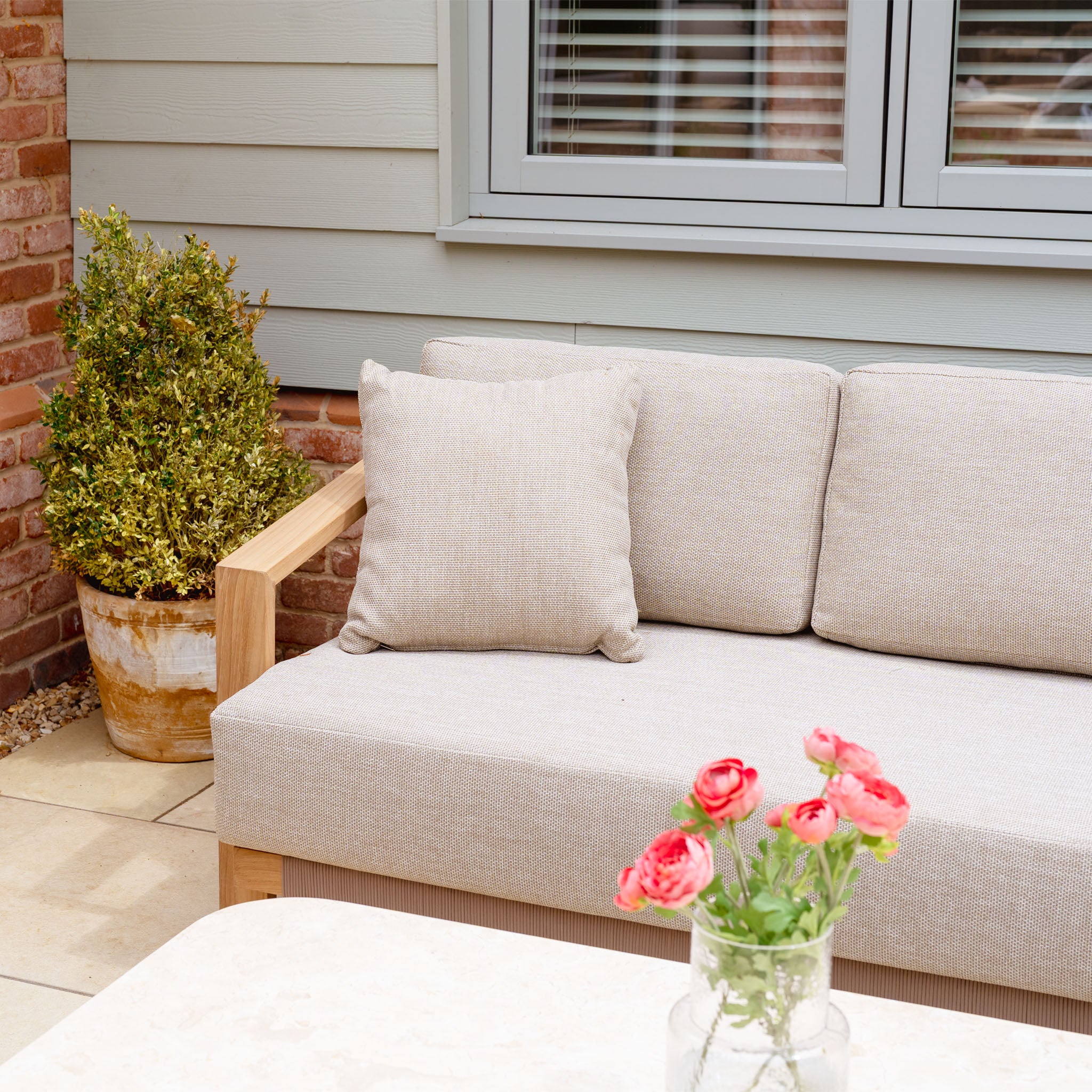 Tivoli 3 Seat Sofa Set with Marble Coffee Table in Fawn, styled with cushions, a potted plant, and a vase of pink flowers on the table in front.