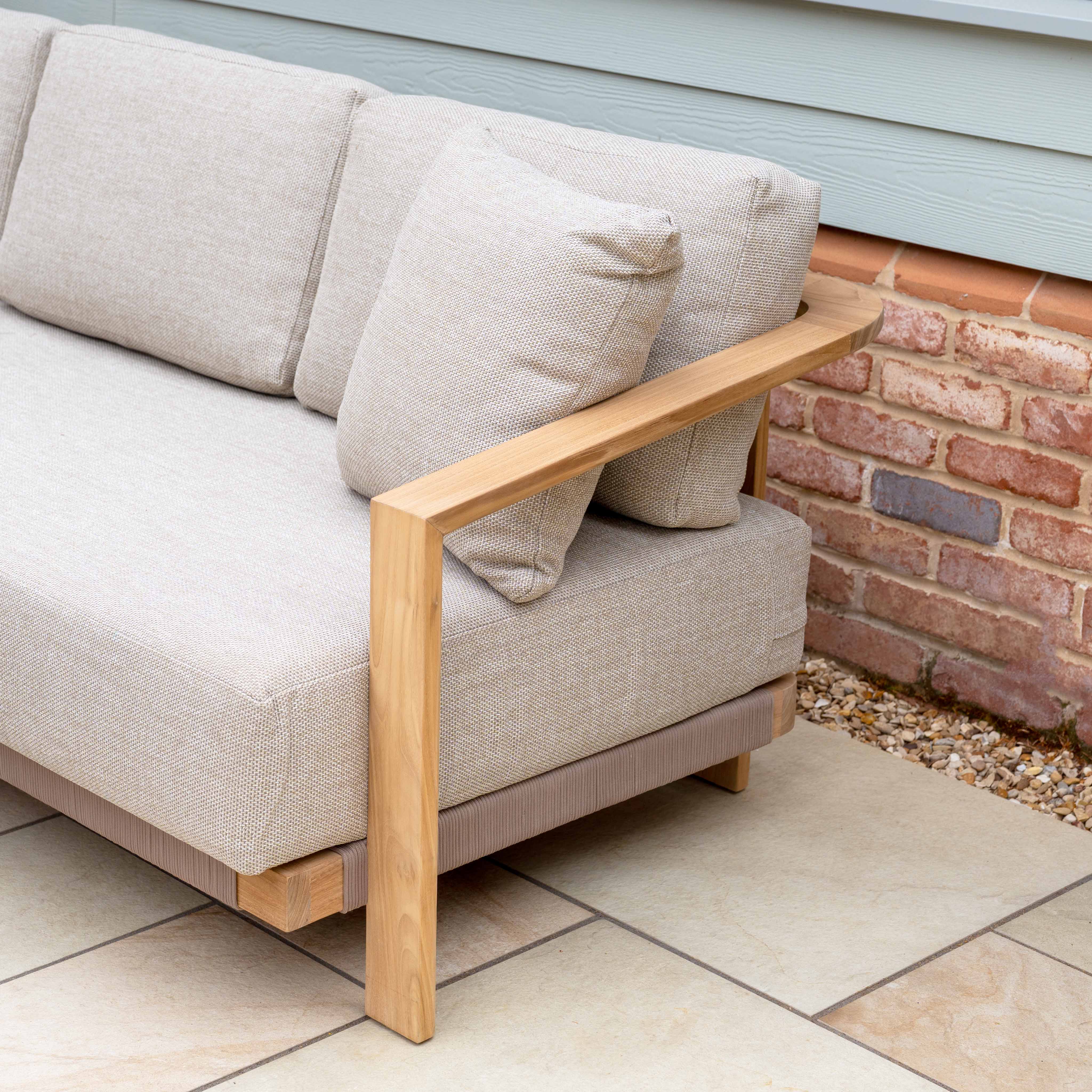 Tivoli 3 Seat Sofa Set with Marble Coffee Table in Fawn, featuring elegant cushions, is displayed on a tiled patio near a brick and siding wall.