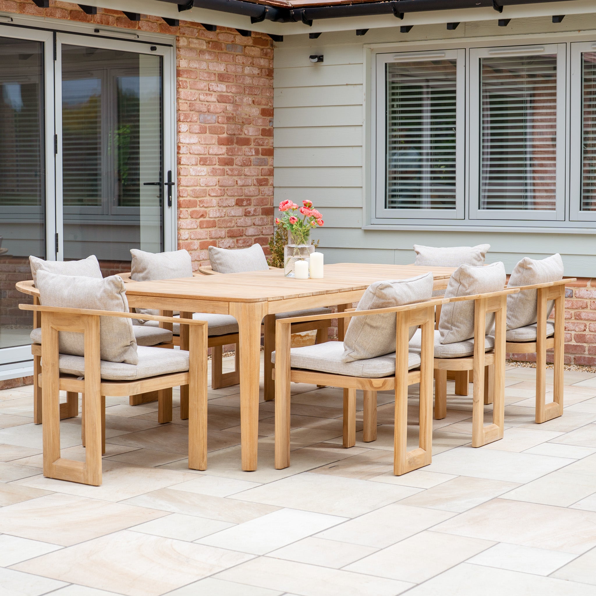 The Tivoli 8 Seat Dining Set with Teak Dining Table in Fawn includes eight cushioned chairs and a durable teak table, perfect for outdoor dining on your patio near the house.