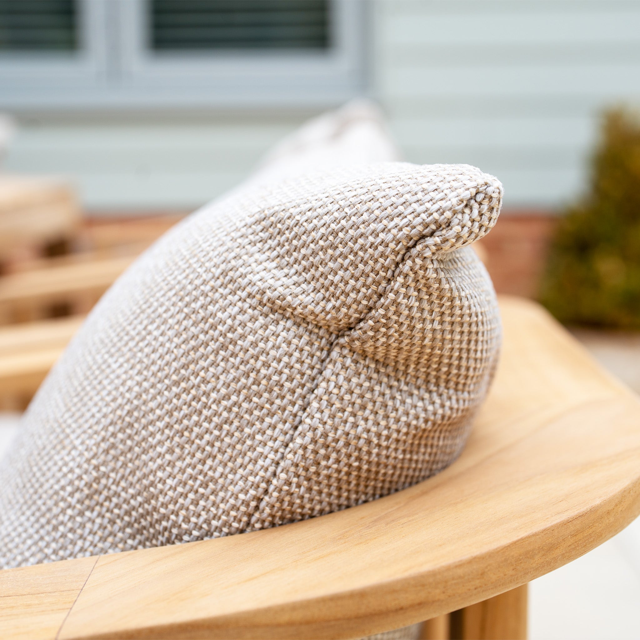 A close-up of the textured, beige UV-resistant cushion on a wooden outdoor chair complements the Tivoli 8 Seat Dining Set with Teak Dining Table in Fawn.
