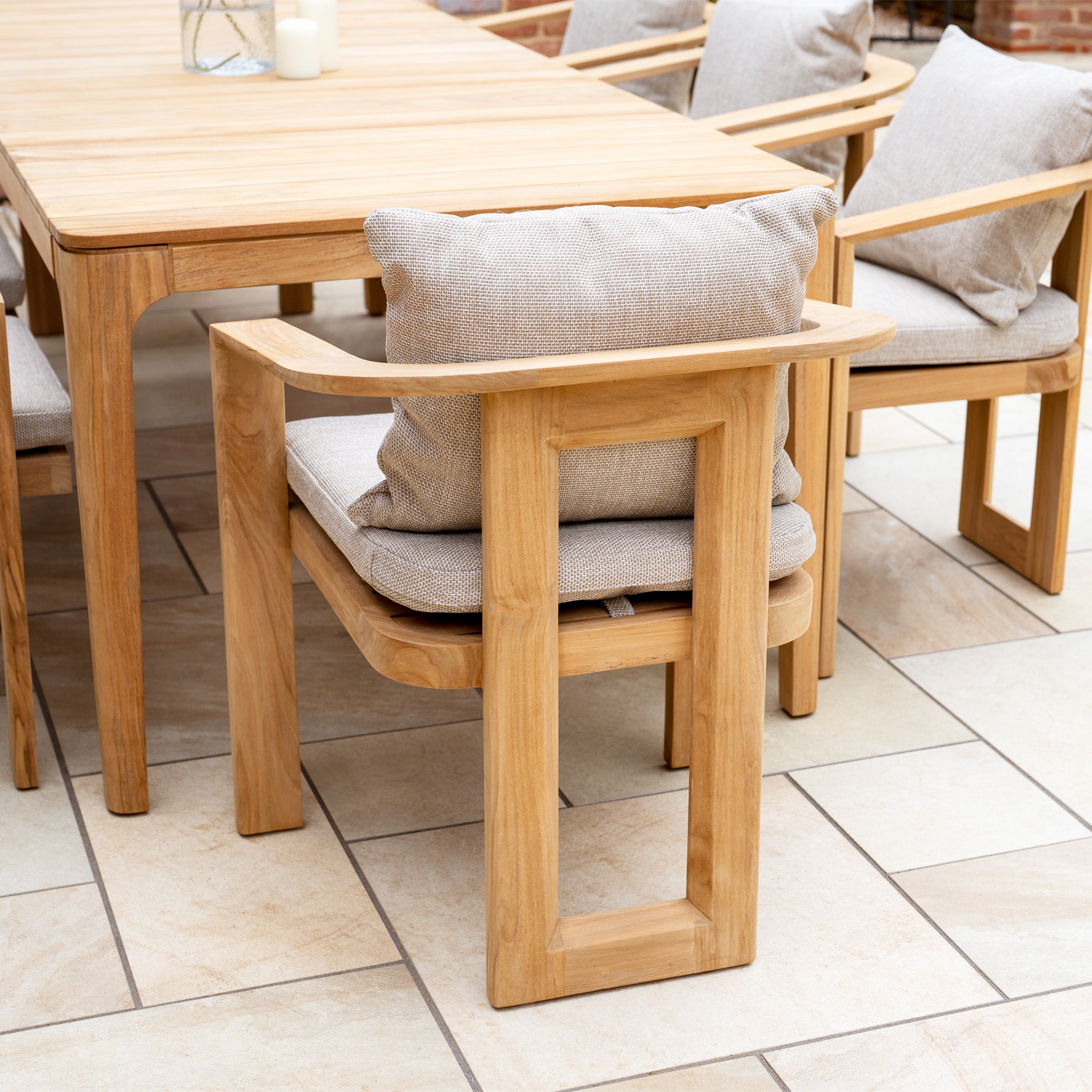The Tivoli 8 Seat Dining Set with Teak Dining Table in Fawn, featuring UV resistant cushions, is displayed on a tiled floor in a bright, modern outdoor setting.