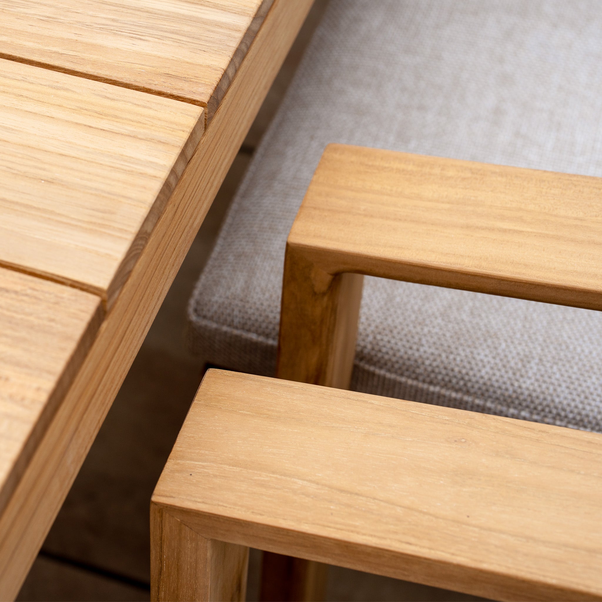 Close-up of the Tivoli 8 Seat Dining Set with a teak dining table and chairs, featuring light gray, UV resistant fawn cushions.